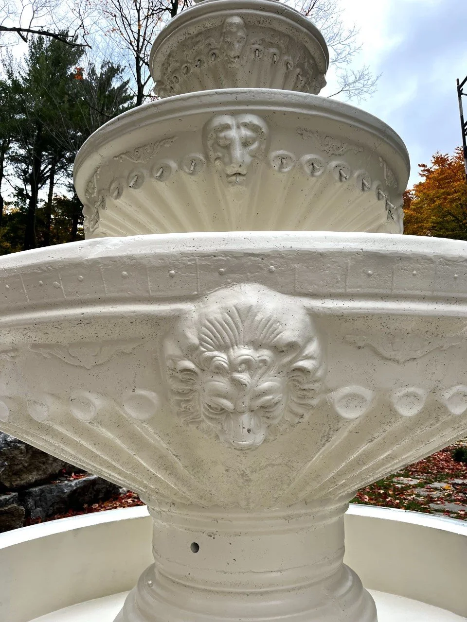 Close-up of a multi-tiered stone fountain with ornate lion head carvings.