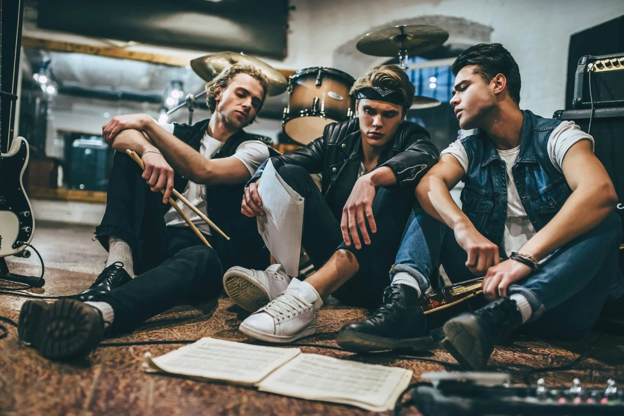Band members rehearsing in a music studio surrounded by instruments and recording equipment