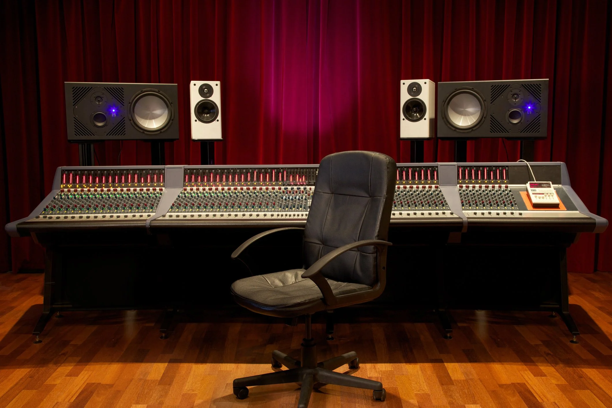 Professional recording studio with large mixing console, monitor speakers, and an office chair