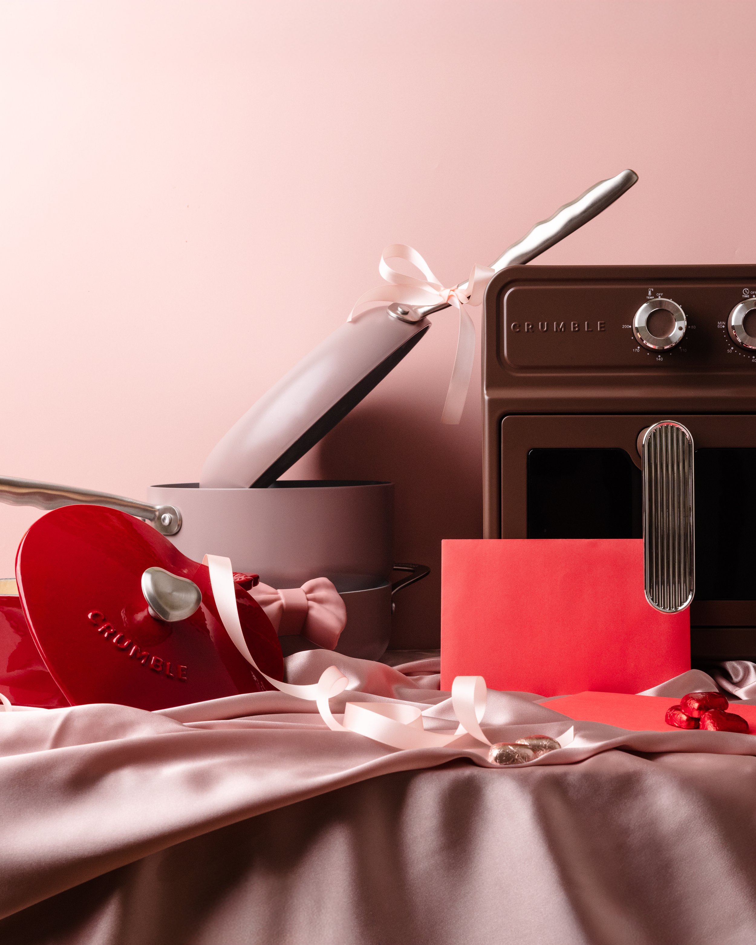Pink and red Valentines Inspired Photoshoot for Crumble cookware featuring pink ceramic pans, red cast iron pot and brown aesthetic airfryer.