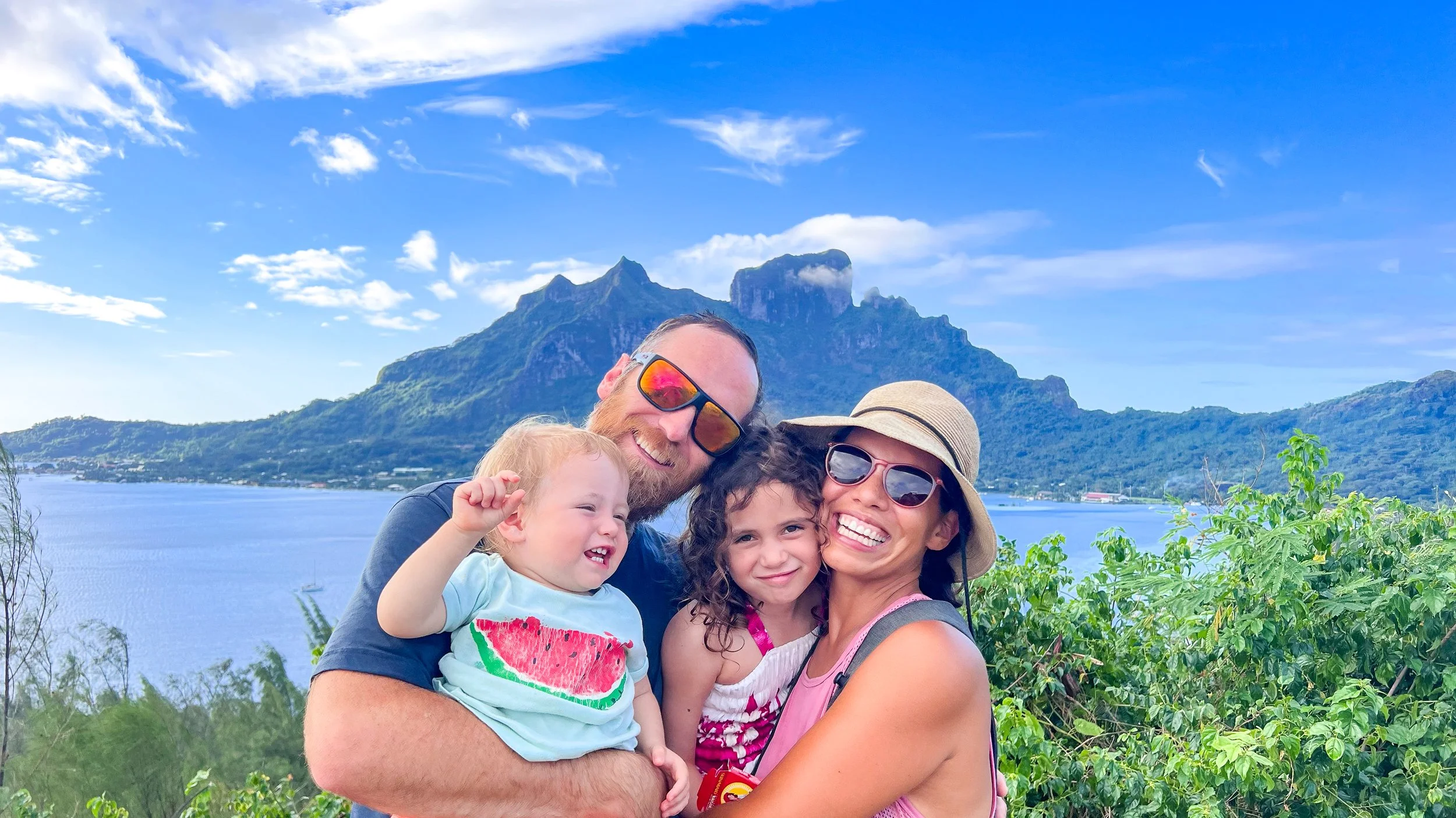 Family with 2 young children with Bora Bora mountain and lagoon behind.