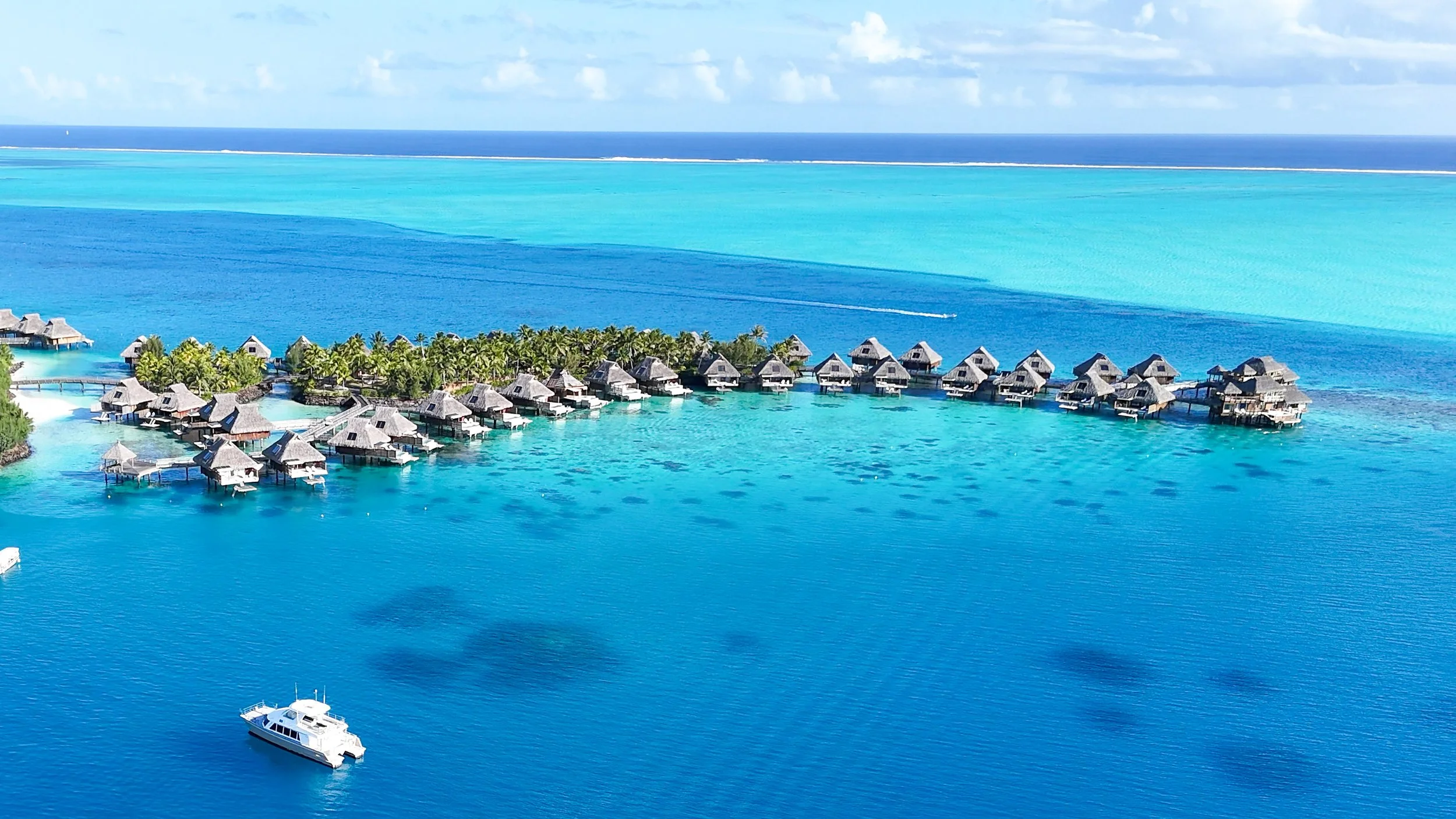 Bora Bora Conrad Hotel aerial view of over water bungalows in turquoise water lagoon with coral below