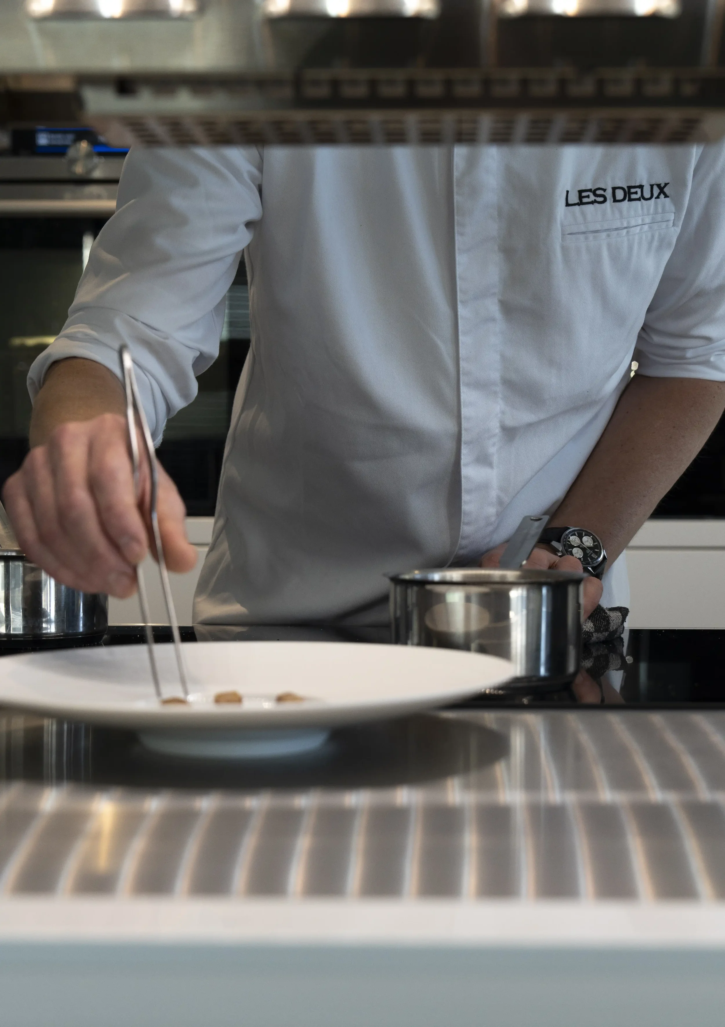 Chef Jan Van Rompaey werkt een gastronomisch gerecht zorgvuldig af tijdens de service.