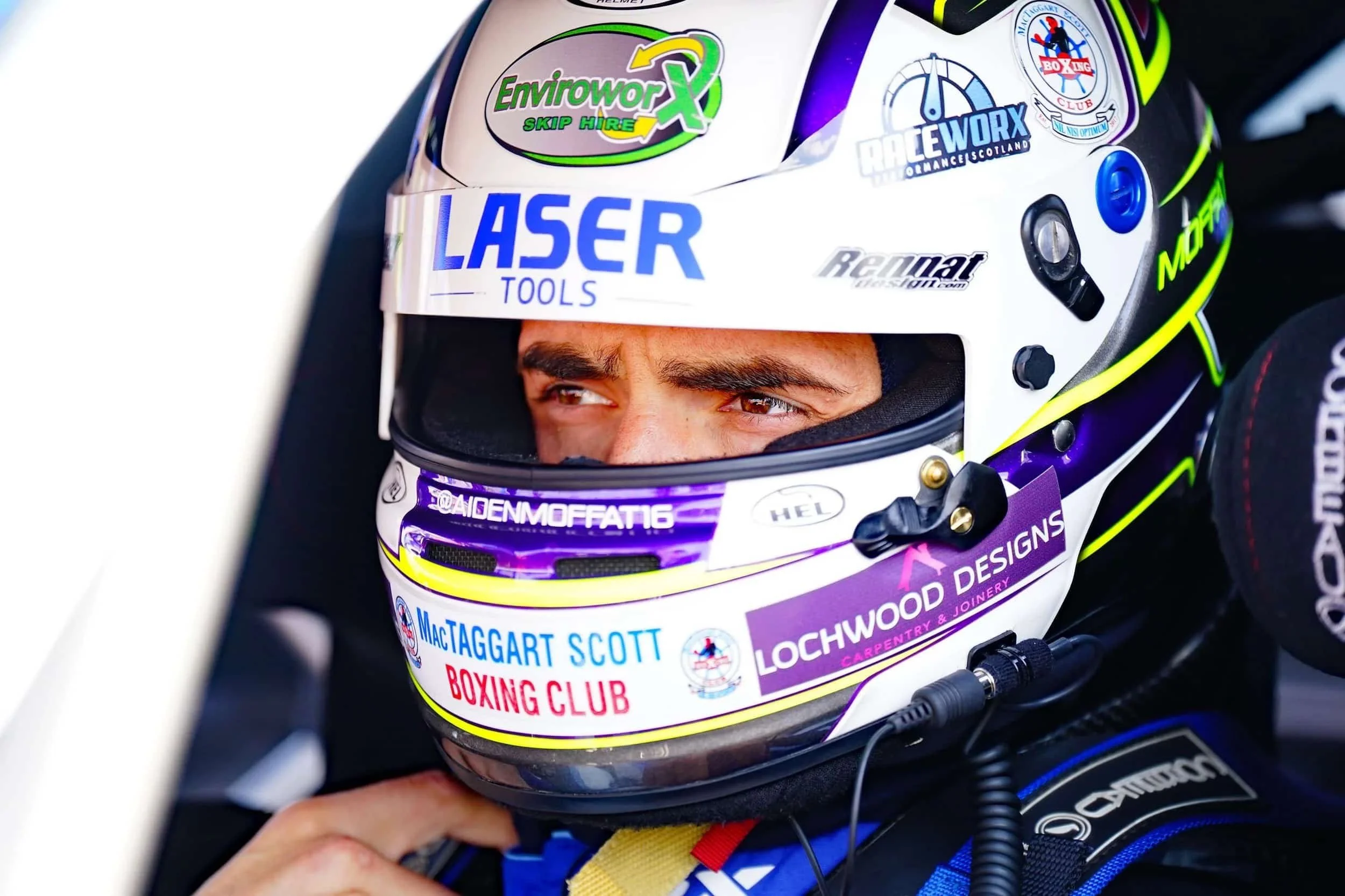 White racing helmet with sponsor logos and a person’s eyes visible