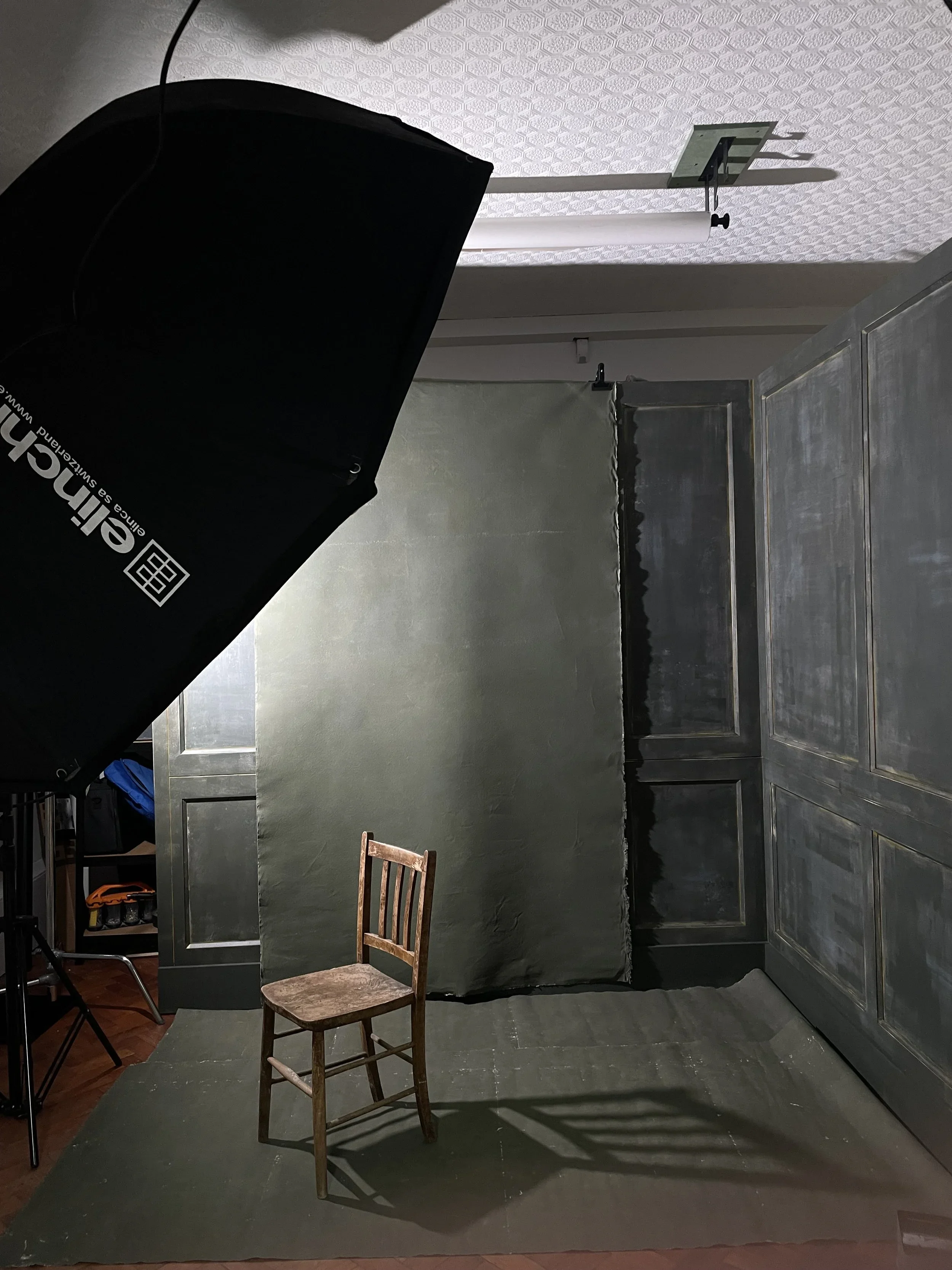 The finished three-sided studio wall with a canvas backdrop, chair and Elinchrom softbox