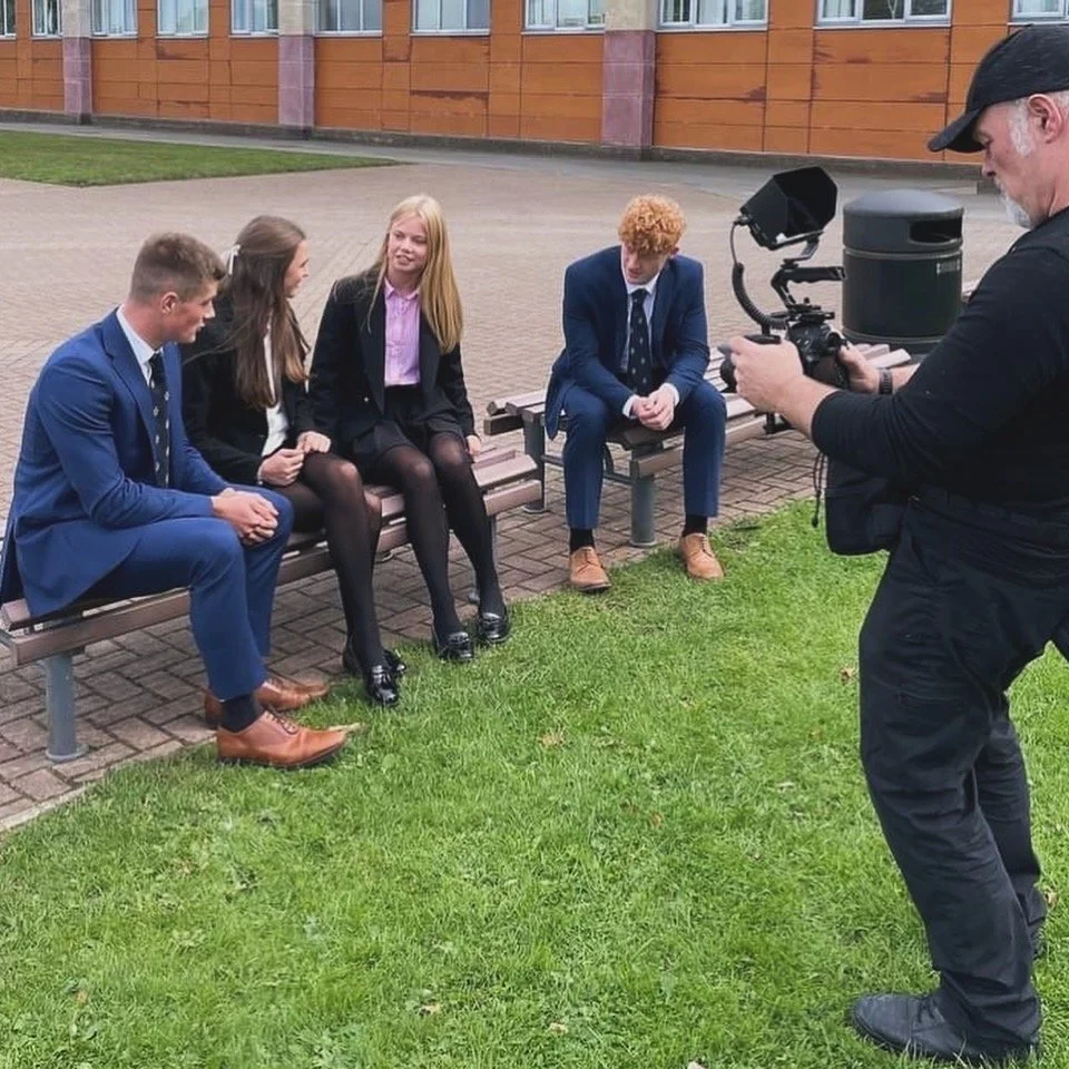 Brett Harkness filming a school promotional video with pupils on a bench