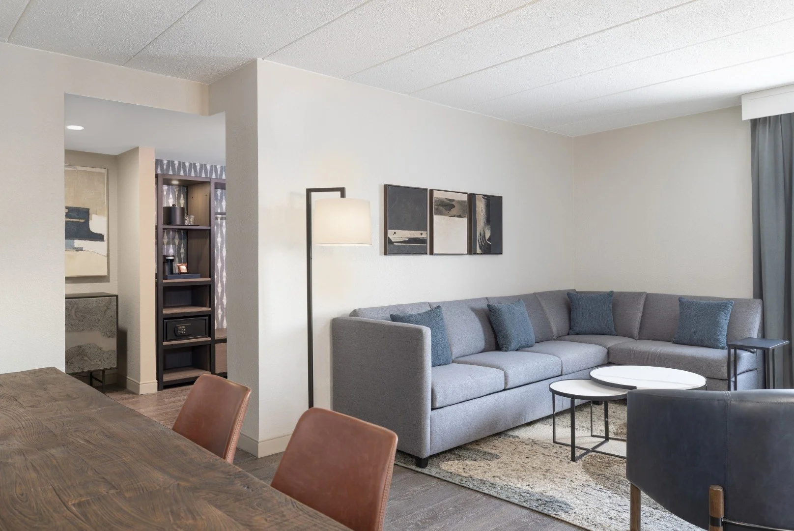 Hotel room with a television, a desk with a chair, a bed, and hallway leading to another room