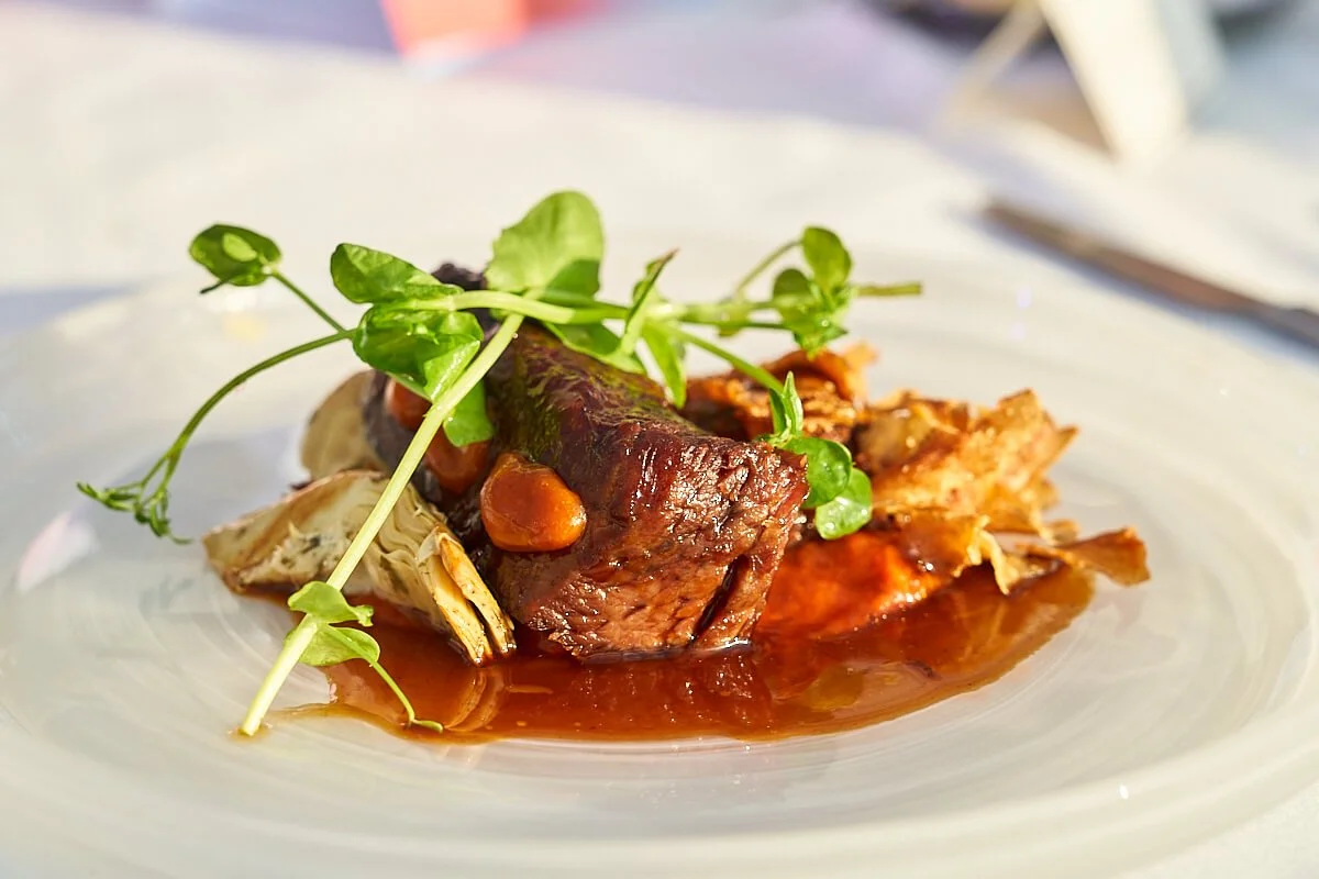 Gerecht met gestoofd vlees, artisanaal saus, aardappel en groenten met wat groene microgreens als garnering.