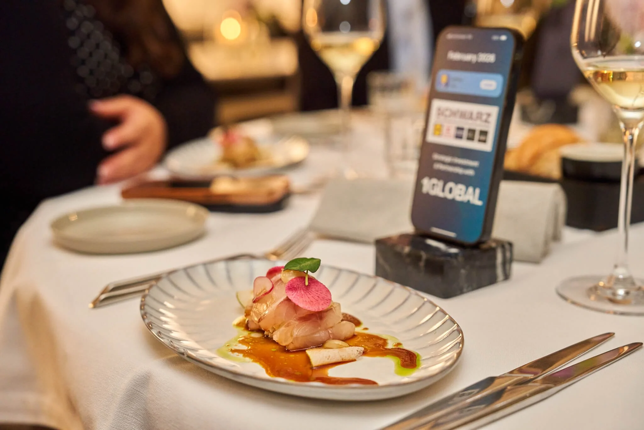 Gereserveerd gerecht op een bord met zalm en garnituur, op een feesttafel met wijn en een menu op een smartphone.