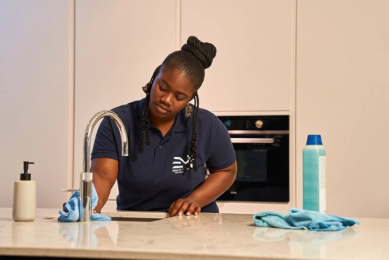 Vrouw poetst het aanrecht in een keuken.