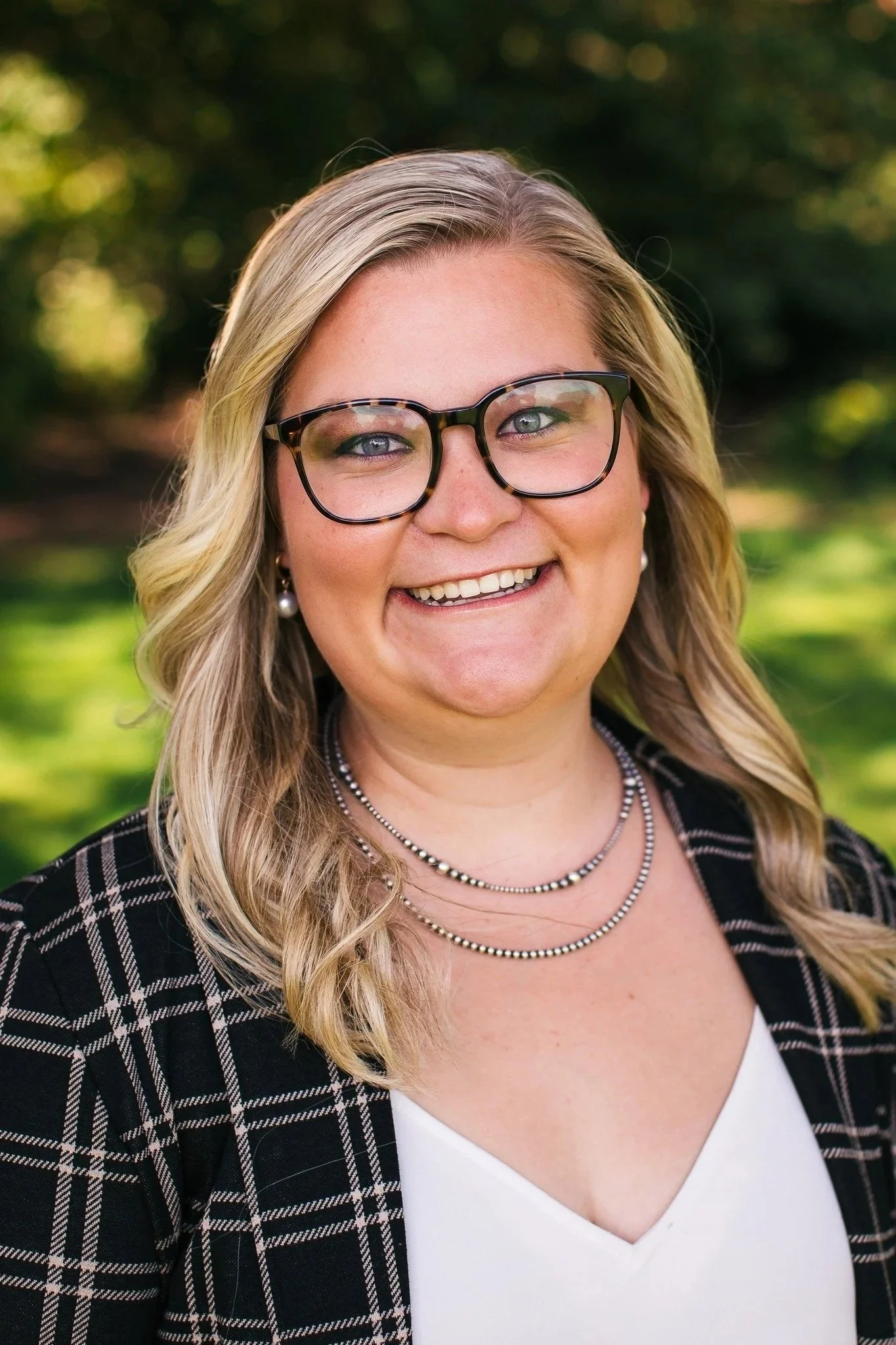 A person wearing a black button-up shirt, standing against a gray background.