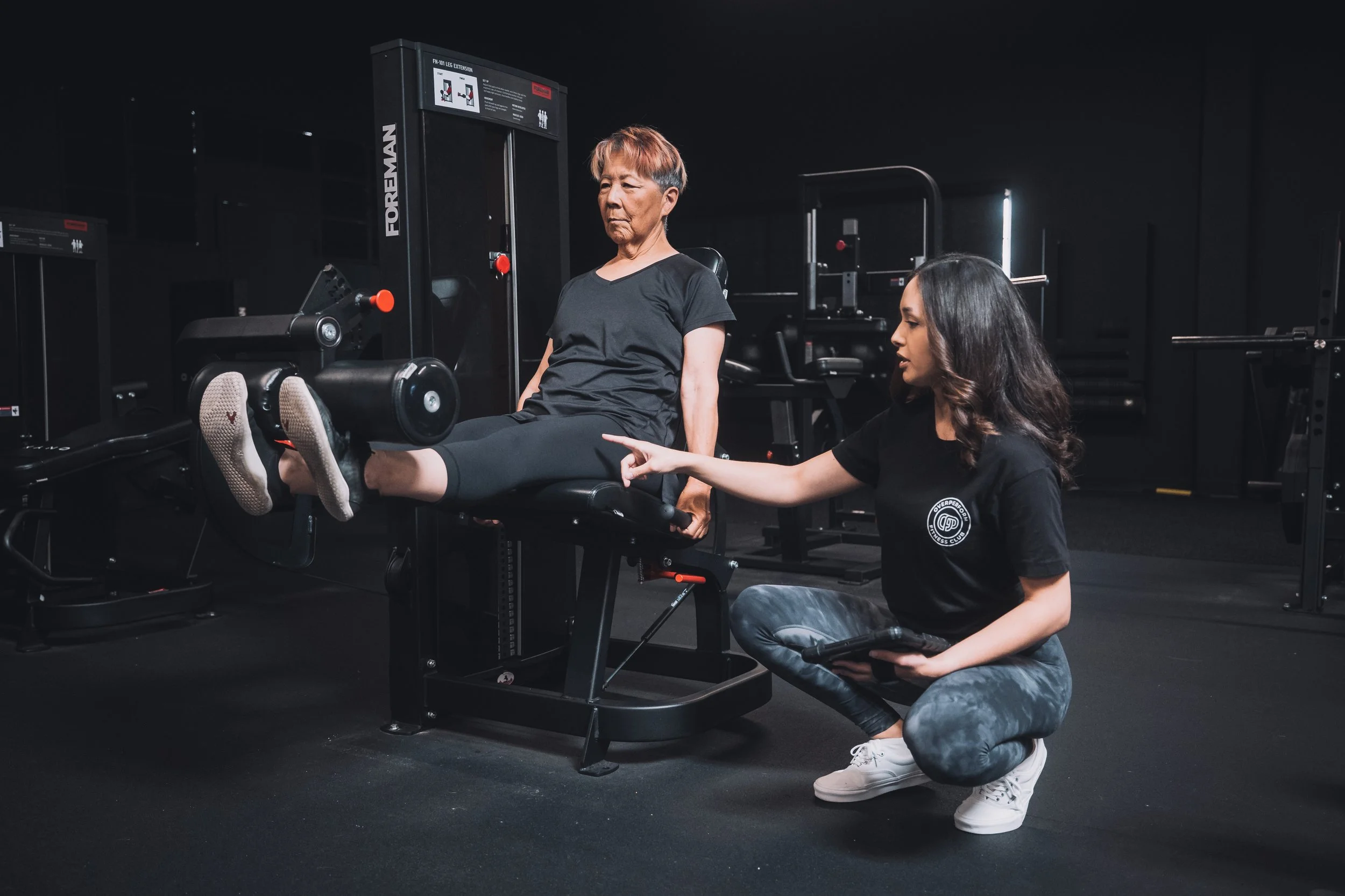 Crown Fitness coach guiding an older adult through a leg-extension for knee strength and mobility—one-on-one personal training in Irvine and Tustin, CA, with form coaching, injury prevention, and custom programs for busy professionals and seniors.