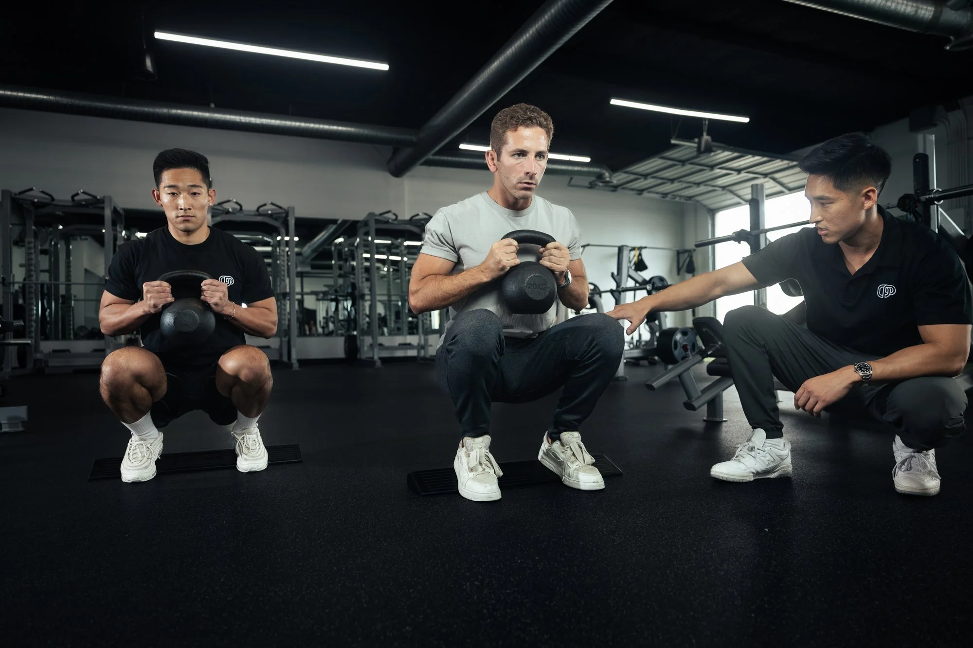 Irvine semi-private coaching—goblet squat with mobility wedges and trainer cues.
SEO description: Crown Fitness coach in Irvine guides two clients through goblet squats using heel wedges to improve depth and mobility. Perfect for executives and busy