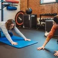 physical therapist working one-on-one with a patient on movement and strength exercises in a clinic setting