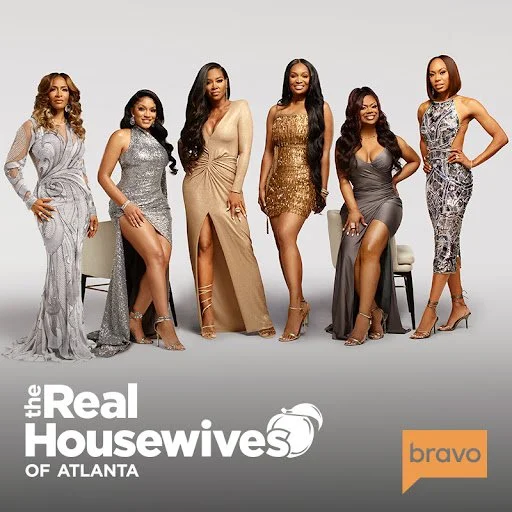 Six women dressed in glamorous evening gowns posing together in a studio for 'The Real Housewives of Atlanta' promotional photo.