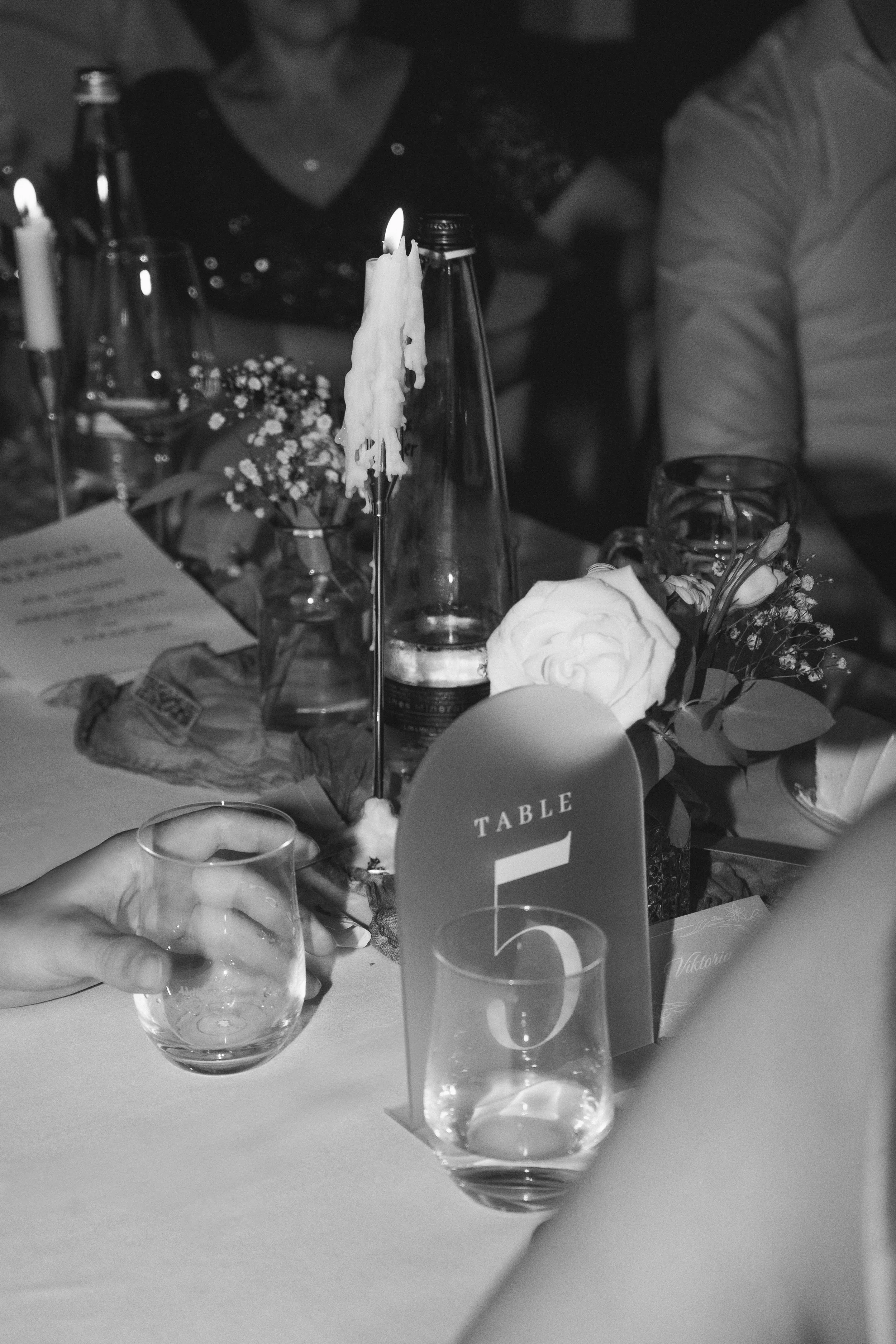 Menschen sitzen an einem festlichen Tisch mit Kerzen, Gläsern, Blumen und Dekorationen bei einer Feier oder Veranstaltung.