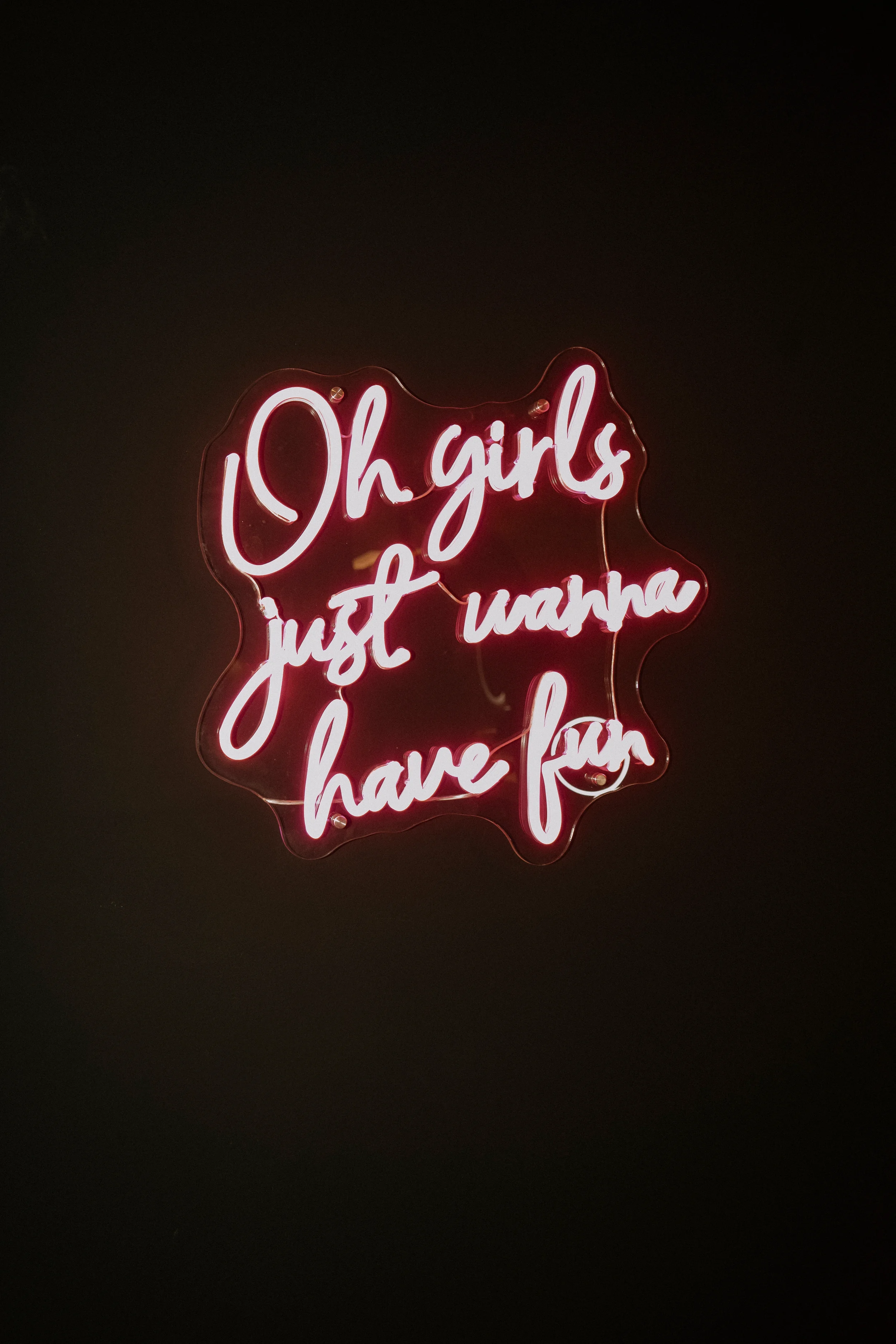 Neon-Schriftzug mit der Aufschrift "Oh girls just wanna have fun" auf schwarzem Hintergrund.