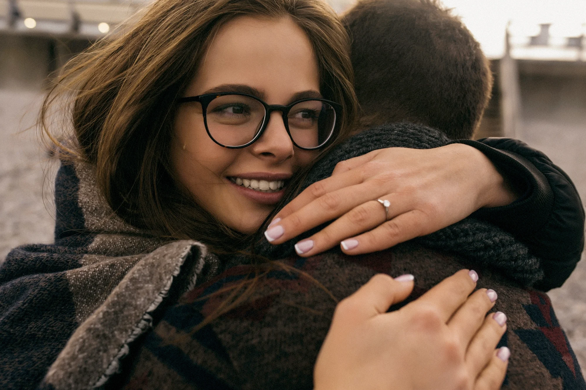 Frau mit Verlobungsring umarmt ihren Partner während eines emotionalen Paarshootings