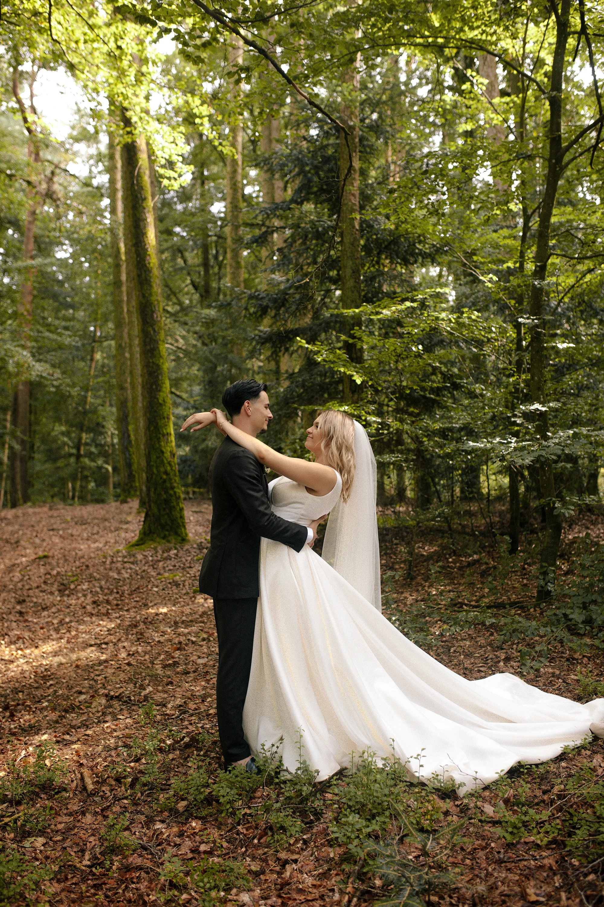 Ein Brautpaar steht sich im Grünen, umgeben von Bäumen, und tanzt im Wald.