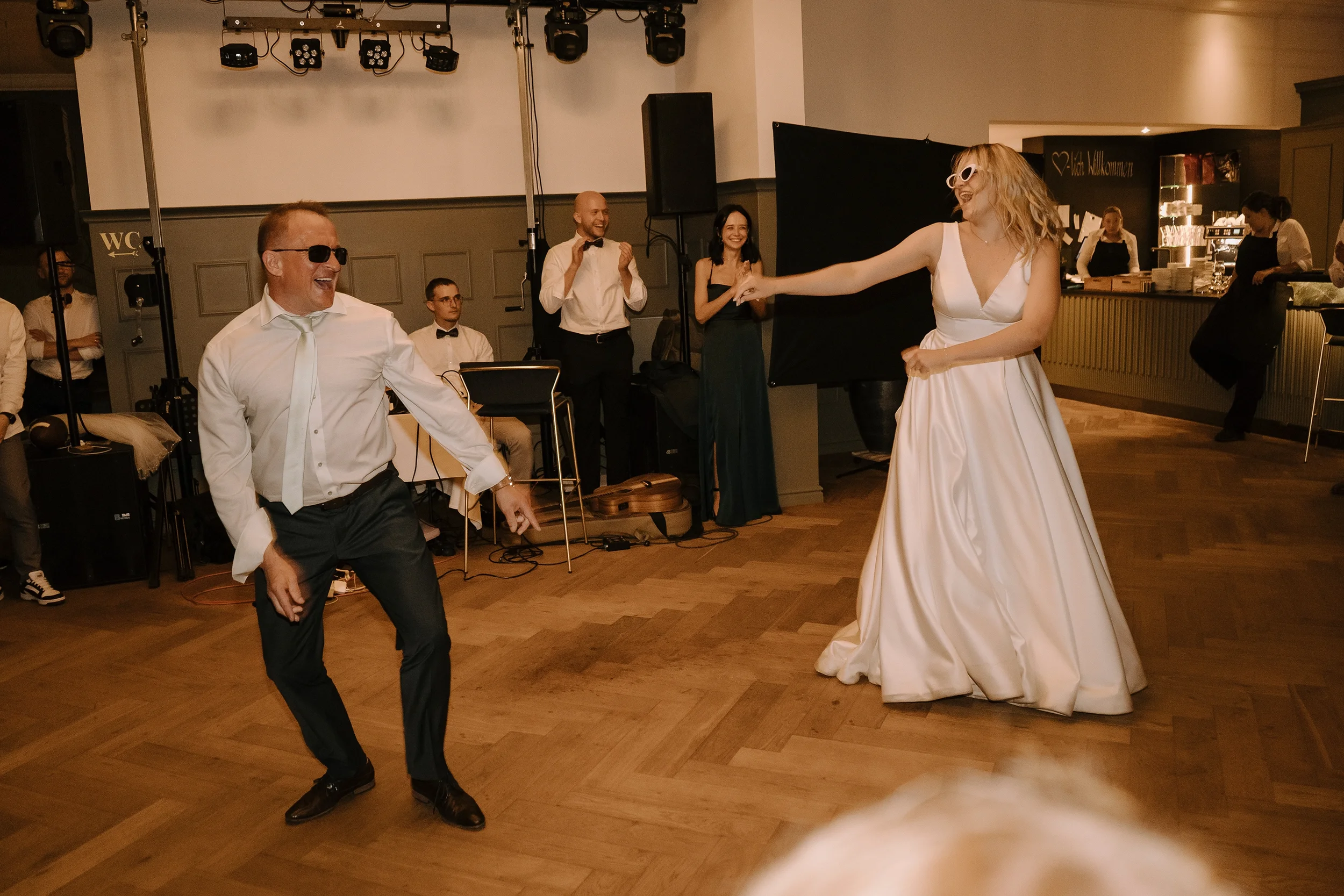 Menschen tanzen auf einer Hochzeitsparty im festlichen Ambiente, mit einem Brautpaar im Mittelpunkt, die glücklich lachen und Spaß haben.