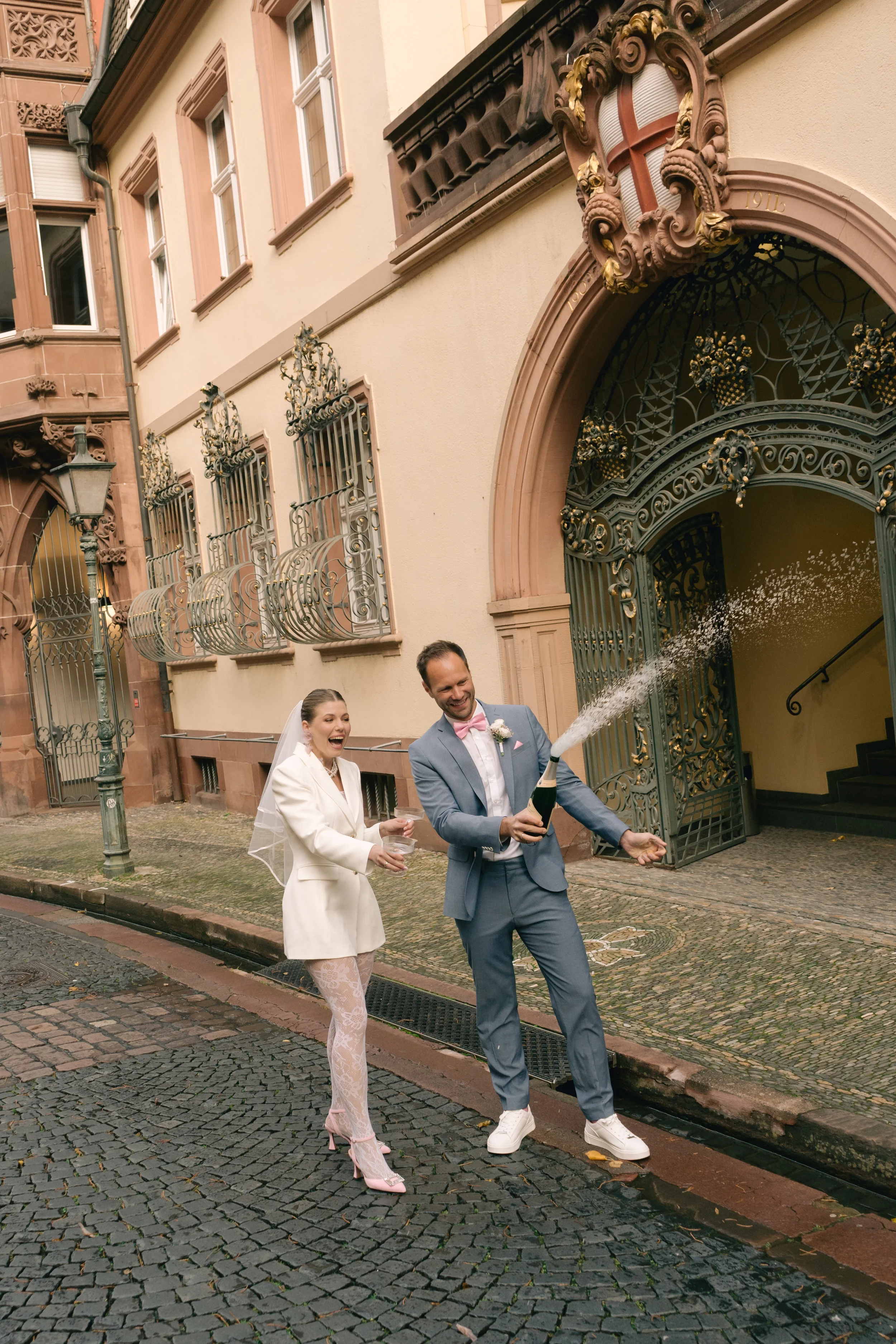 Ein Mann und eine Frau feiern wahrscheinlich eine Hochzeit auf einer Straße, der Mann hält eine Flasche Champagner Standesamt Freiburg