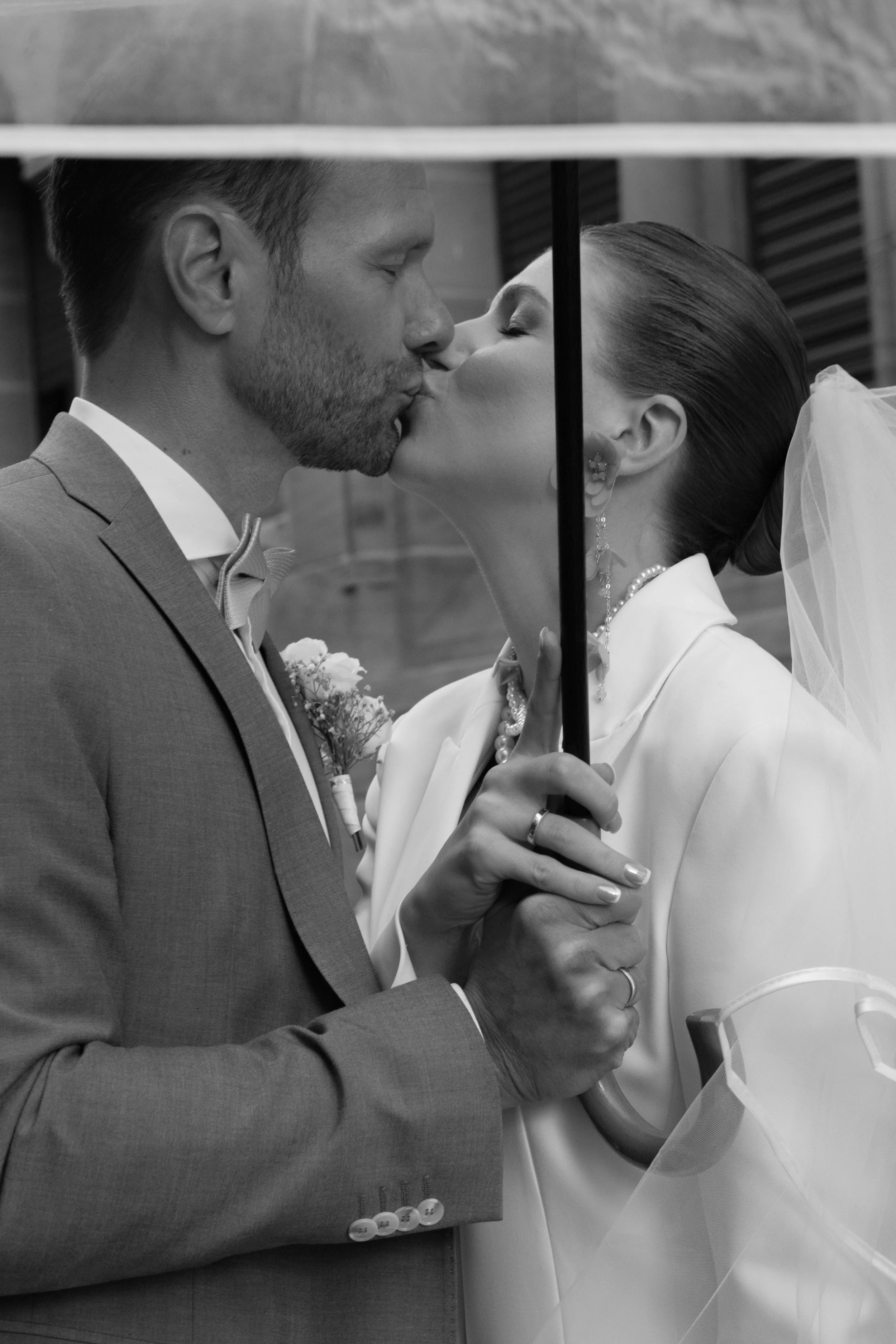Braut und Bräutigam küssen sich unter einem Regenschirm während ihrer Hochzeit.