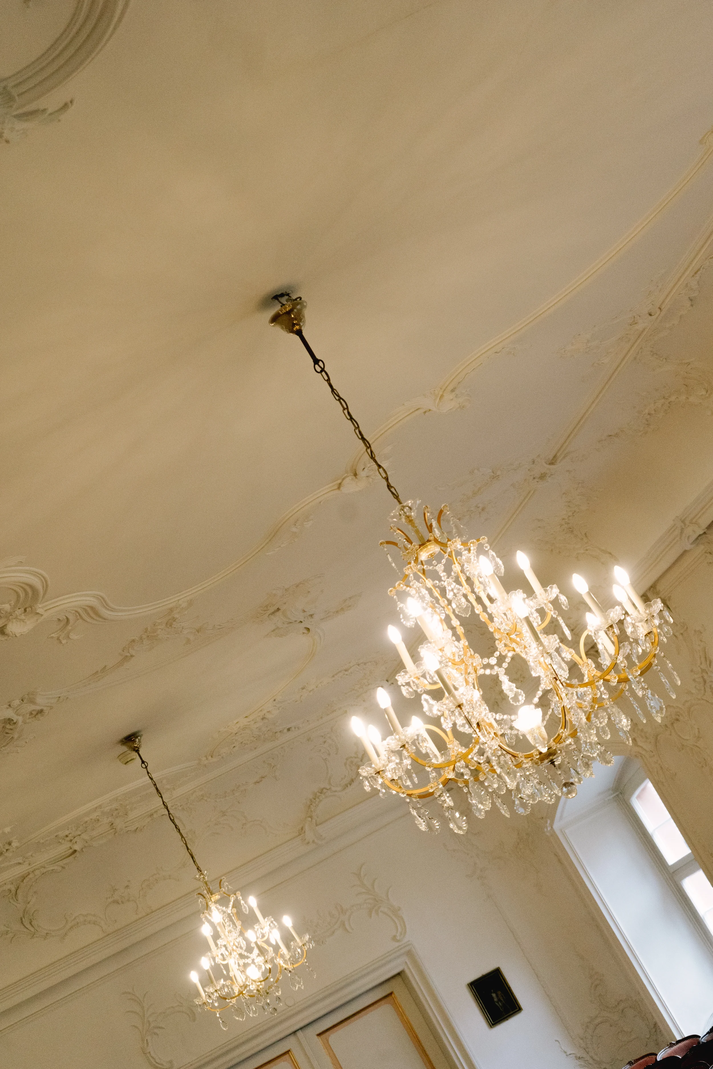 Sehr eleganter Raum mit mehreren Kronleuchtern an einer verzierten weißen Decke.