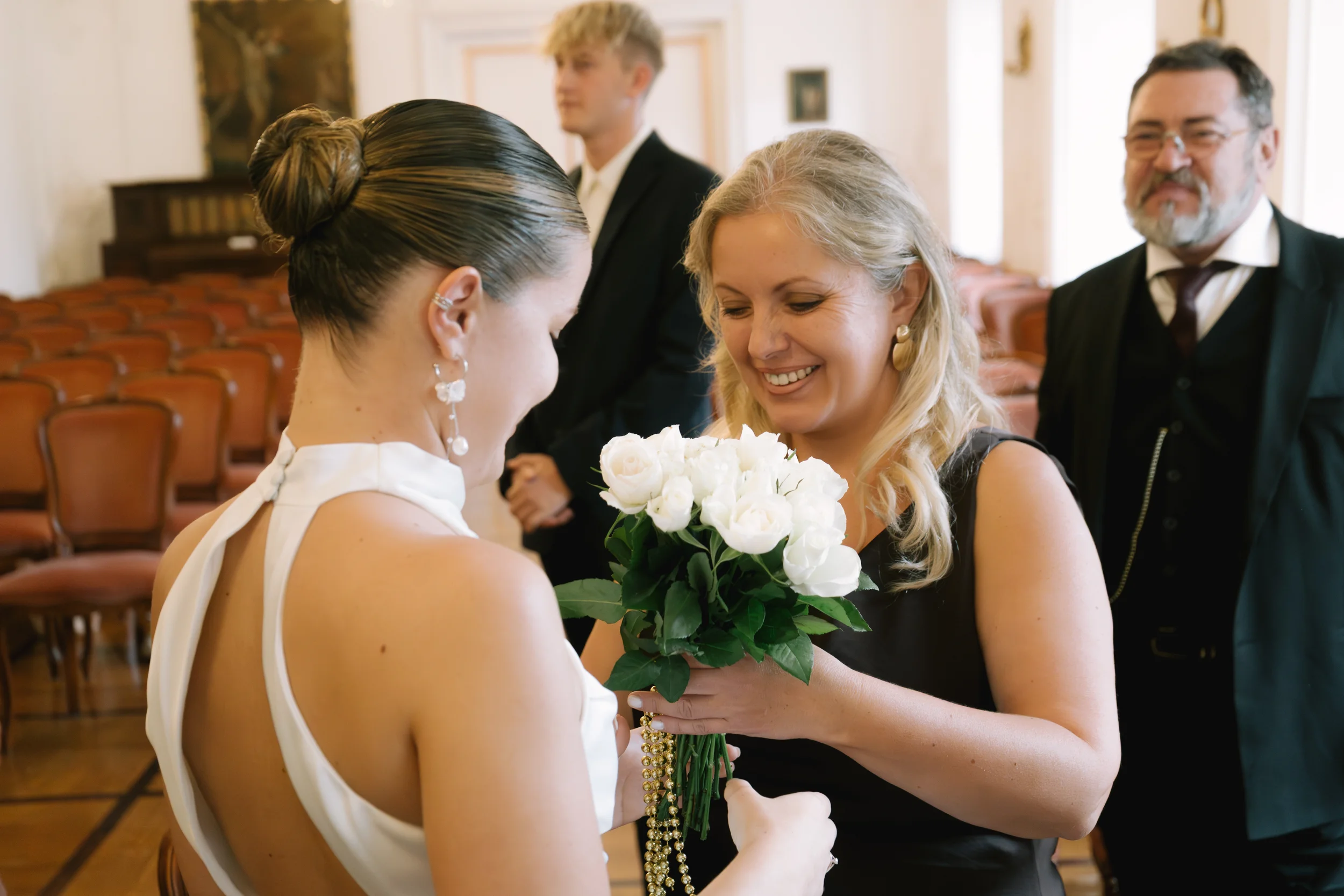 Zwei Frauen schenken sich bei einer Hochzeit Blumen