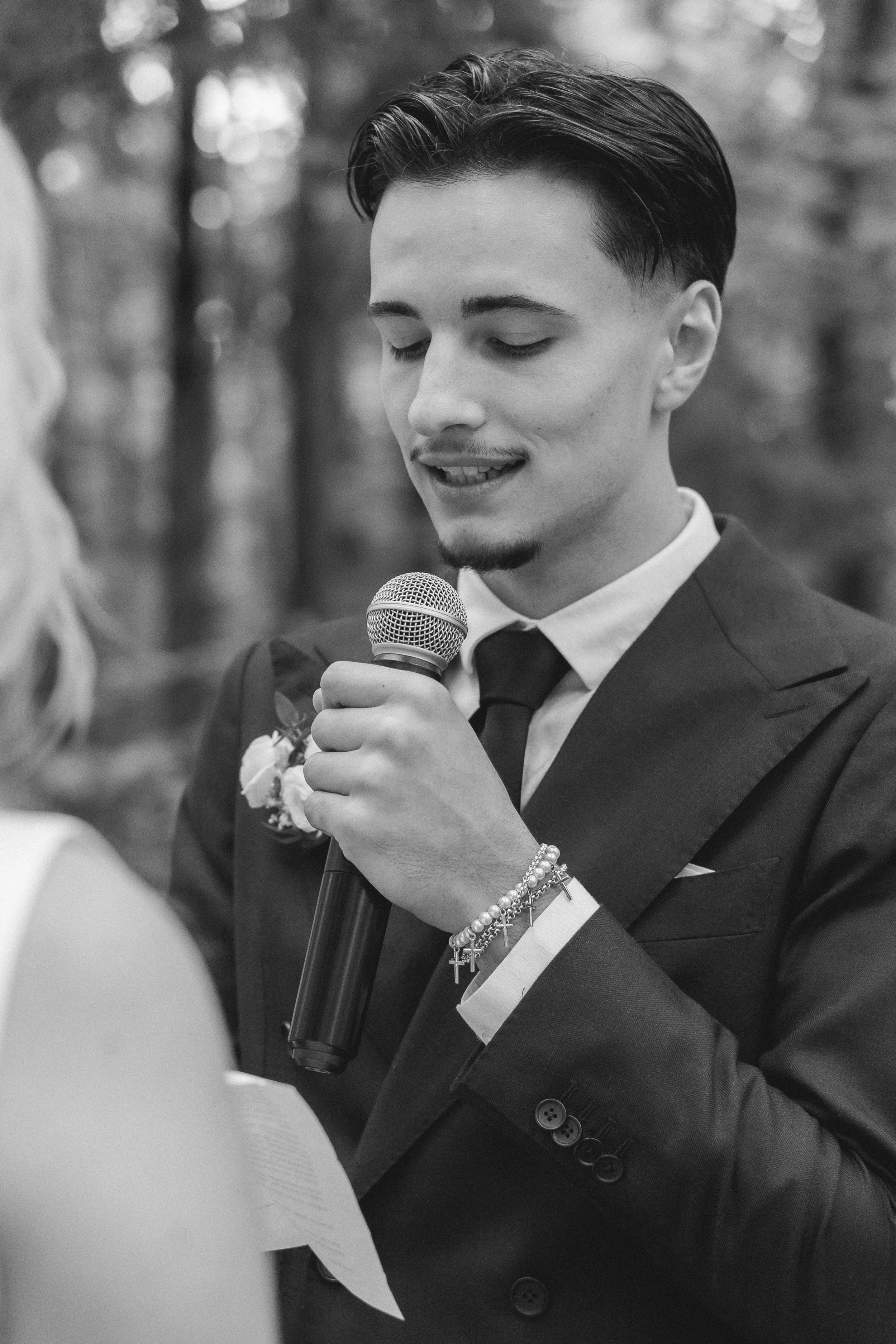 Junge Frau und junger Mann bei einer Zeremonie, möglicherweise Hochzeit, jung, elegant gekleidet, Der Mann hält ein Mikrofon, Bokeh-Hintergrund.