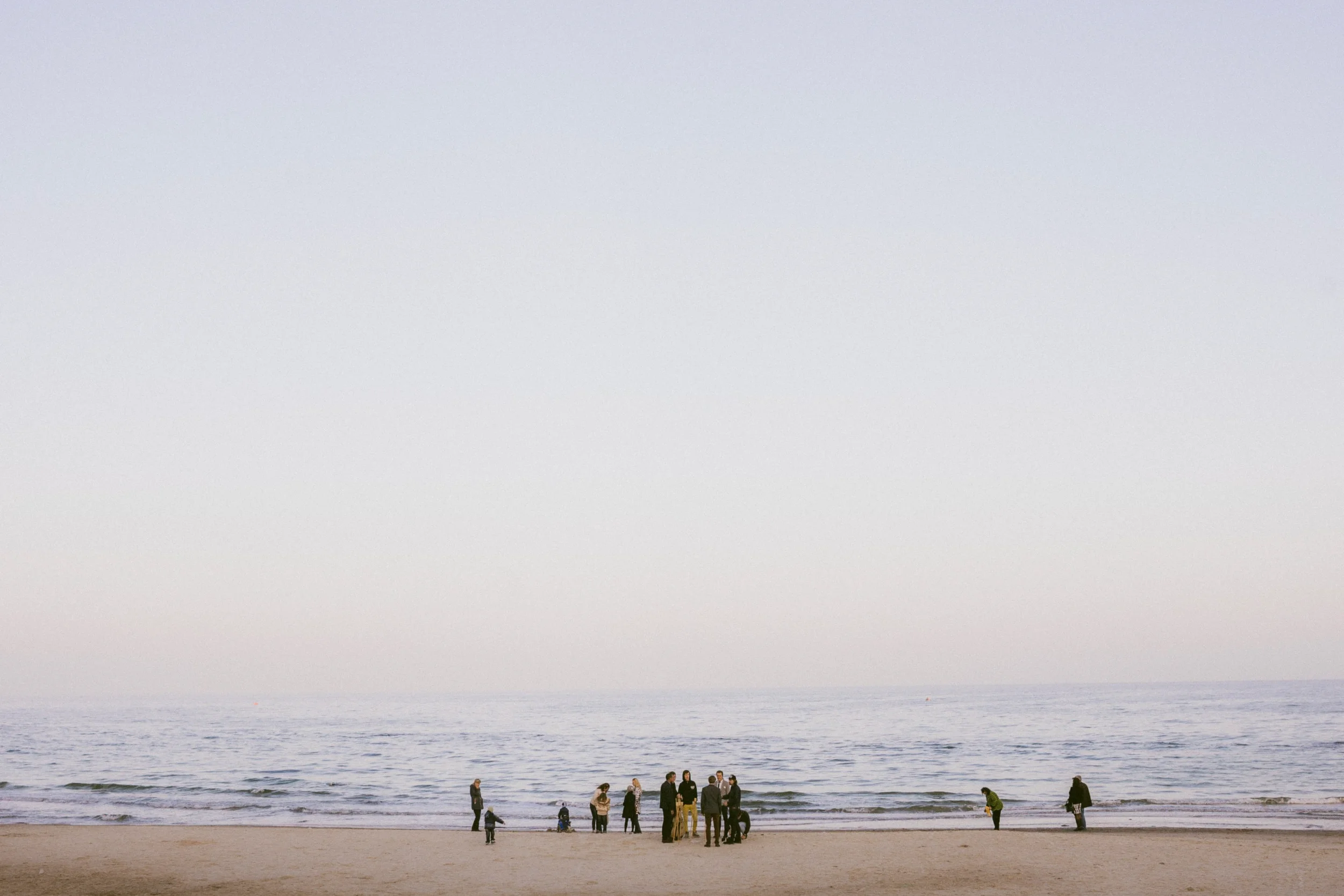 Menschen gehen am Strand entlang, während das Meer im Hintergrund sichtbar ist.