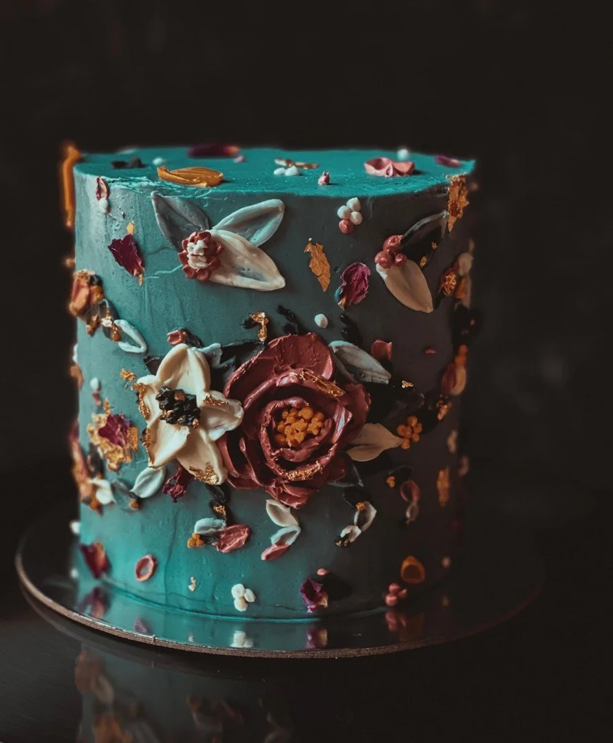 Teal buttercream cake with sculpted deep rose and ivory buttercream flowers, finished with petal details