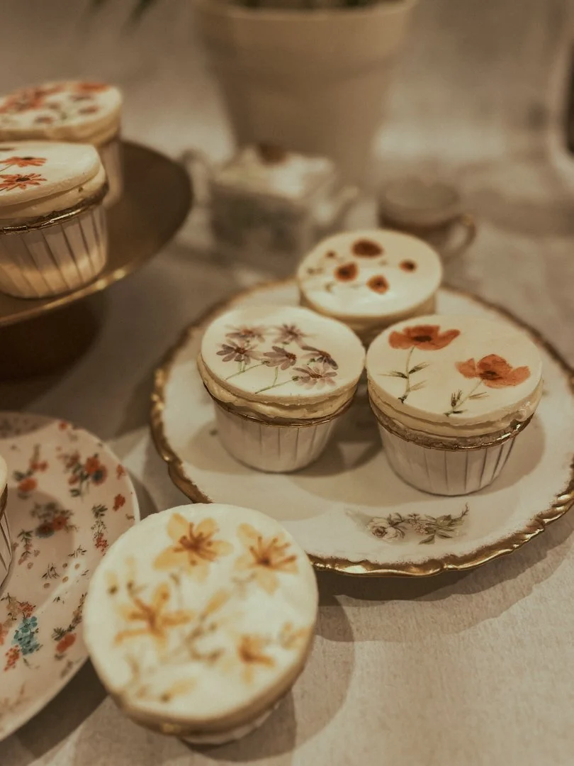 Hand-painted watercolor floral cupcakes displayed on a vintage tray and plates, West Michigan