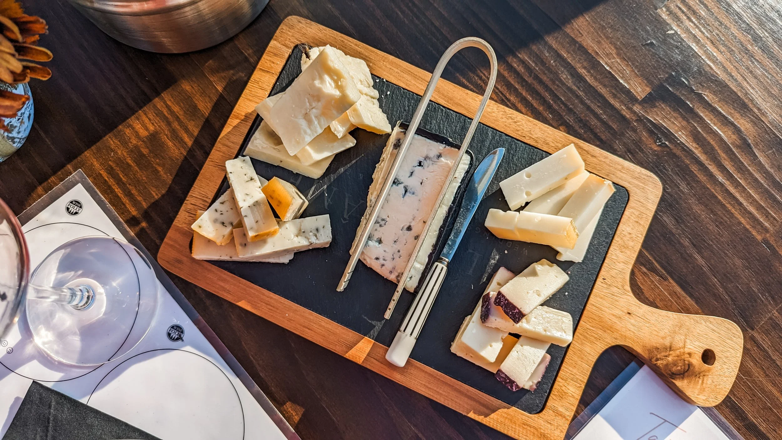 Cheese platter with various types of cheese on a wooden board.