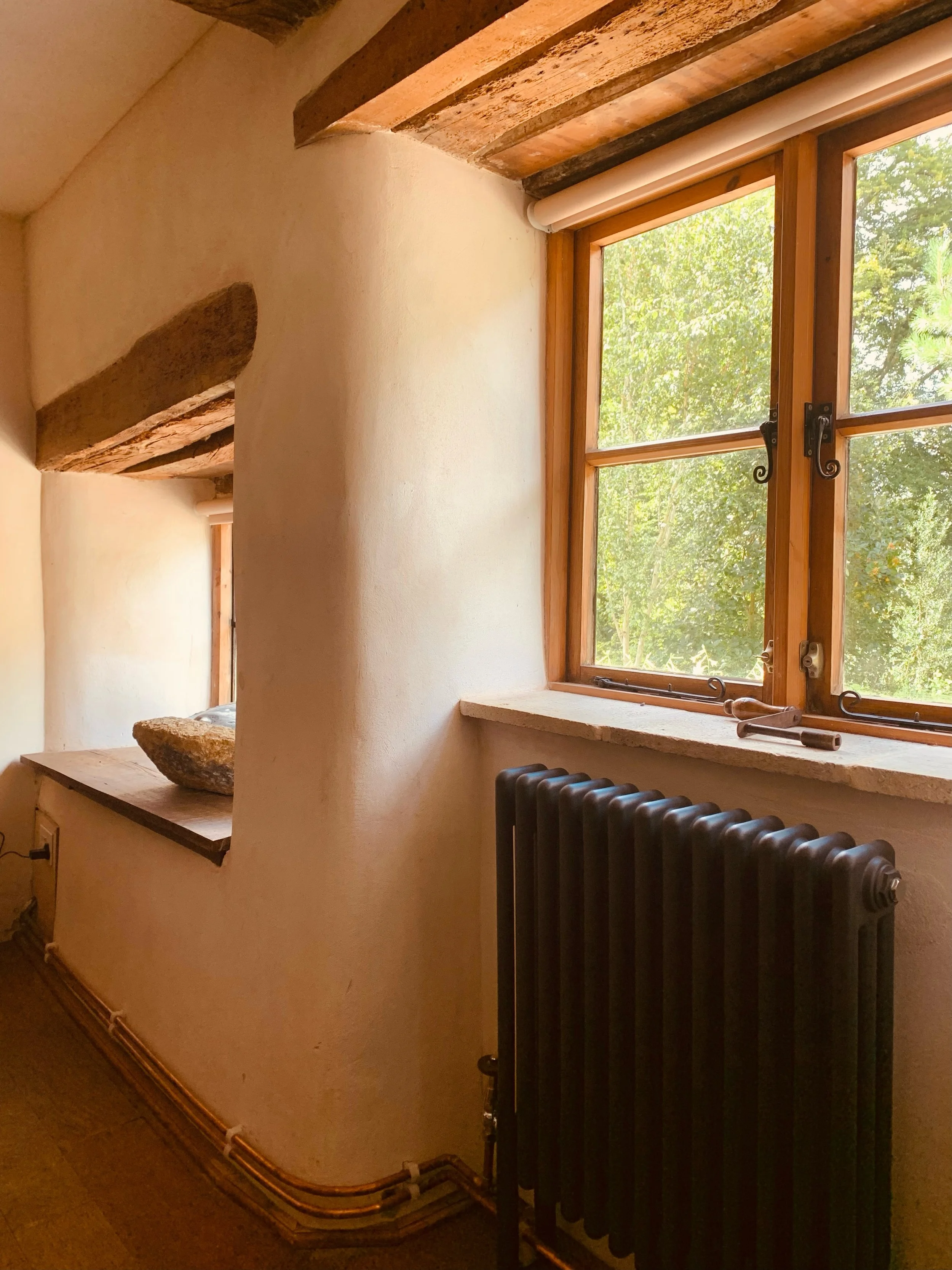 Traditional Lime Plaster onto stone wall with cast iron radiator and new timber windows installed