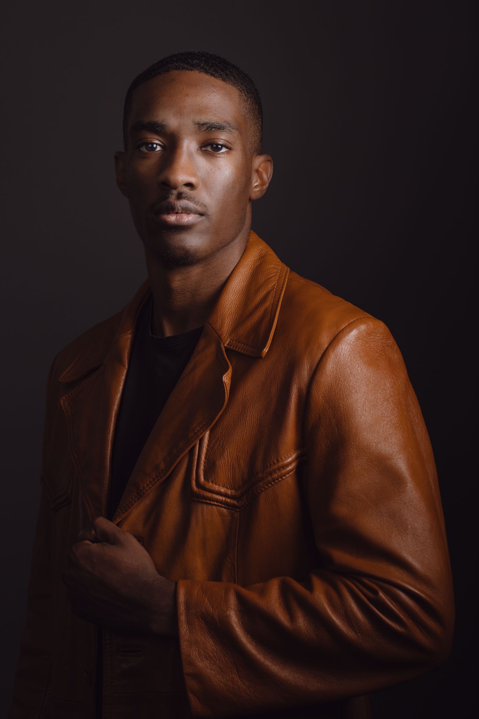 a dramatic photo of a young man wearing a leather jacket