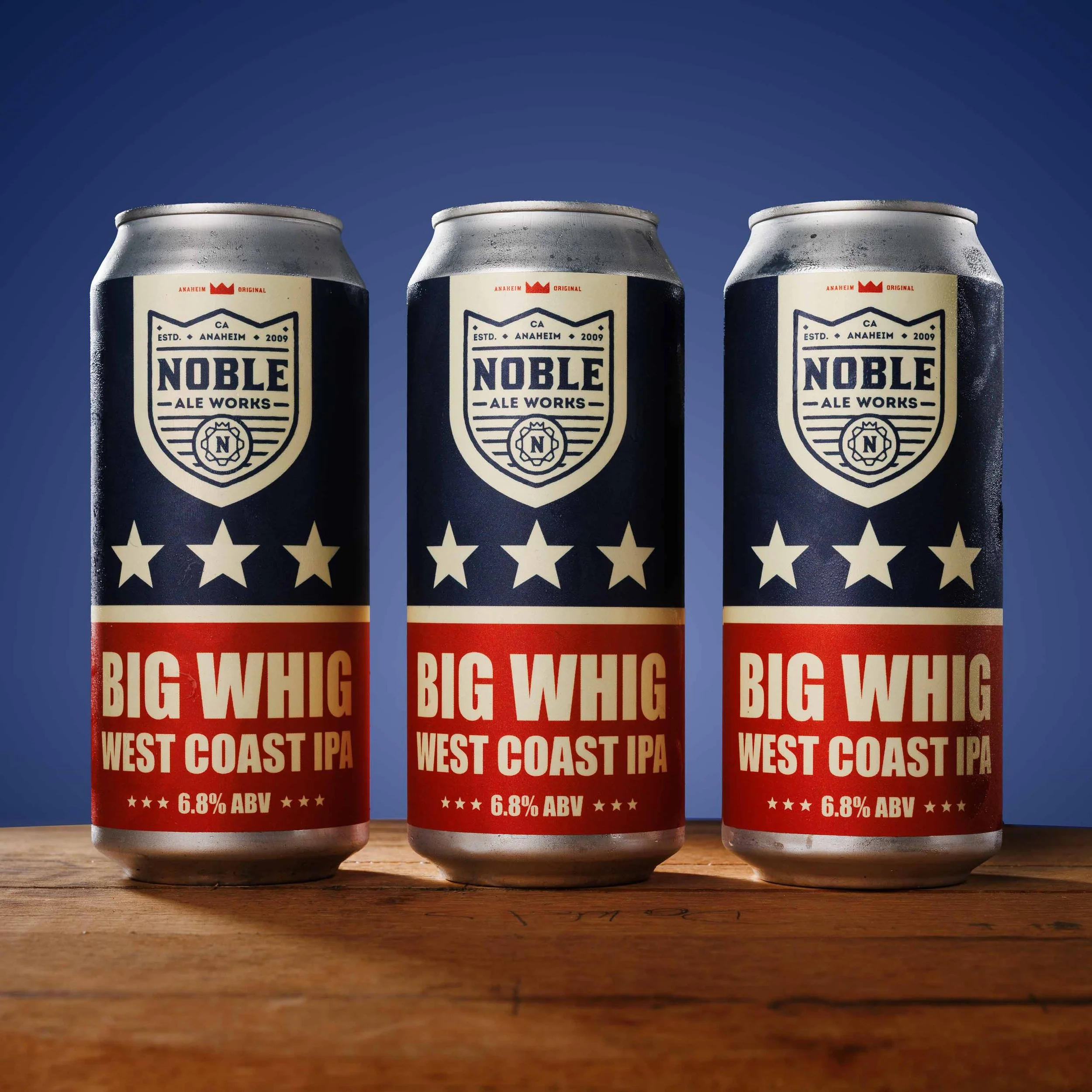 Product photo of three beer cans on a wood surface