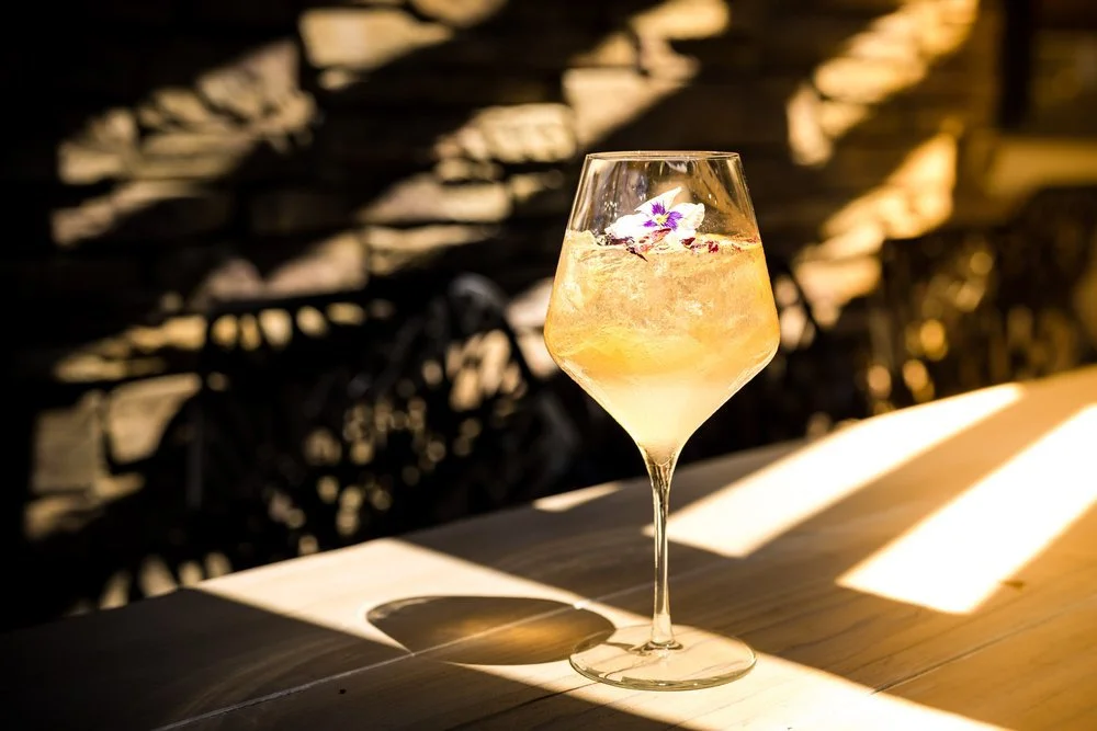 cocktail in a tall glass with late afternoon sun in the background
