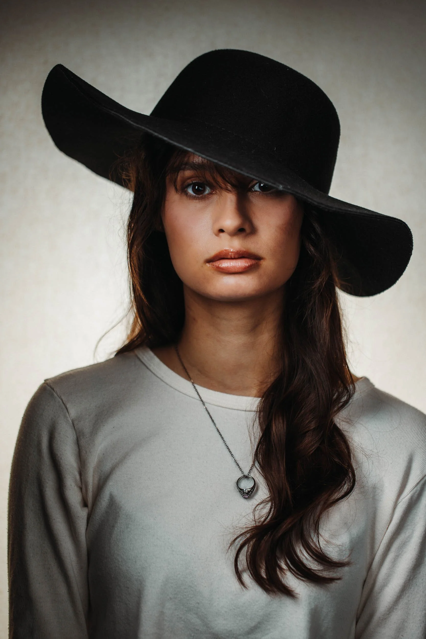 a portrait of a young woman wearing a black hat