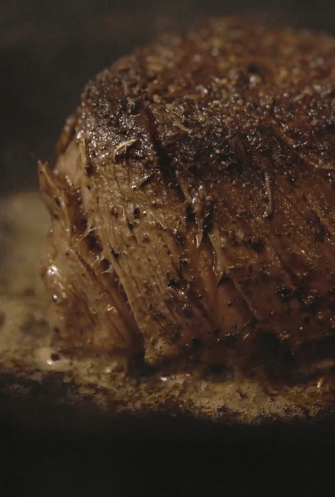 a closeup of a seasoned steak sizzling