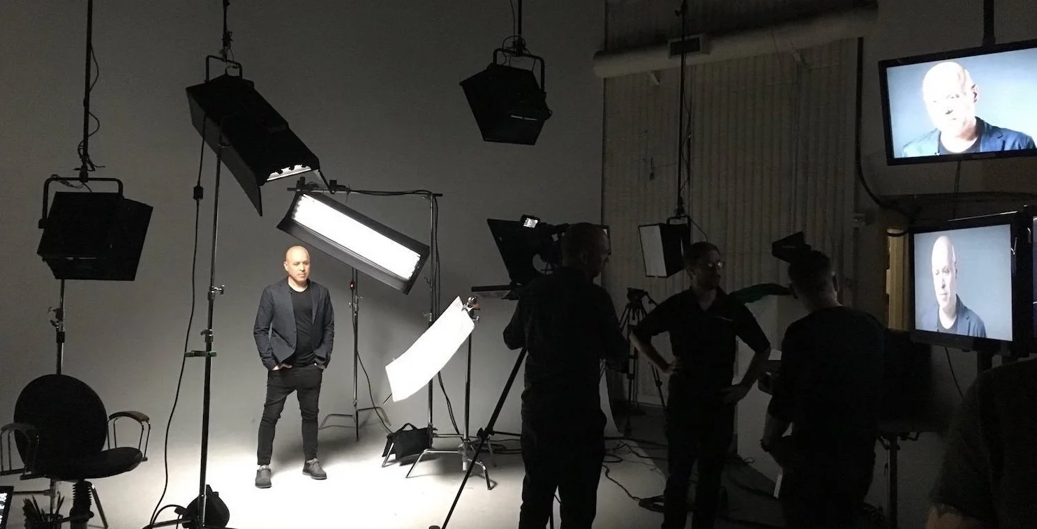 Professional photo or video shoot setup with lighting, cameras, and crew.