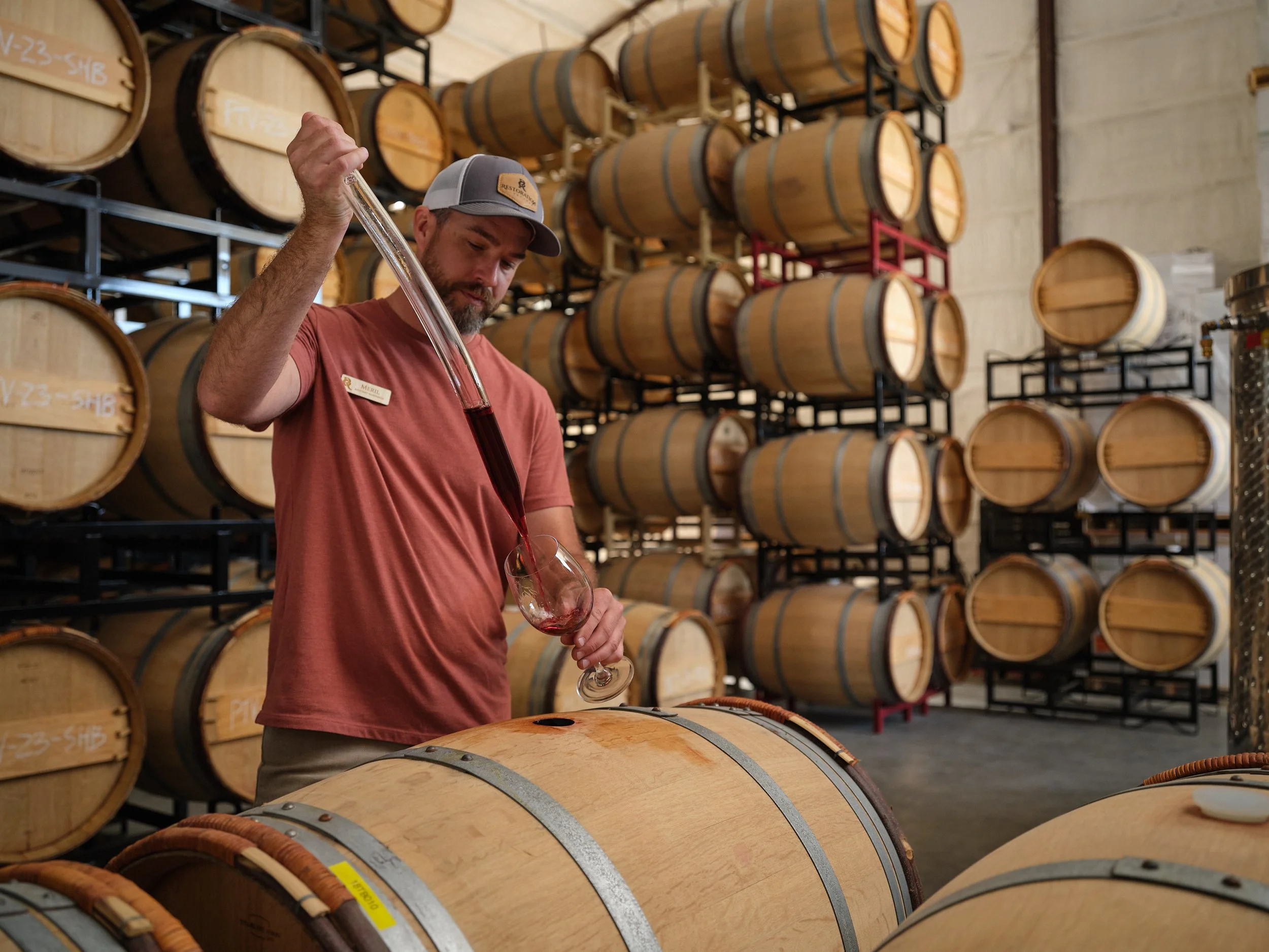 Man in wine barrel room using a spout to test wine