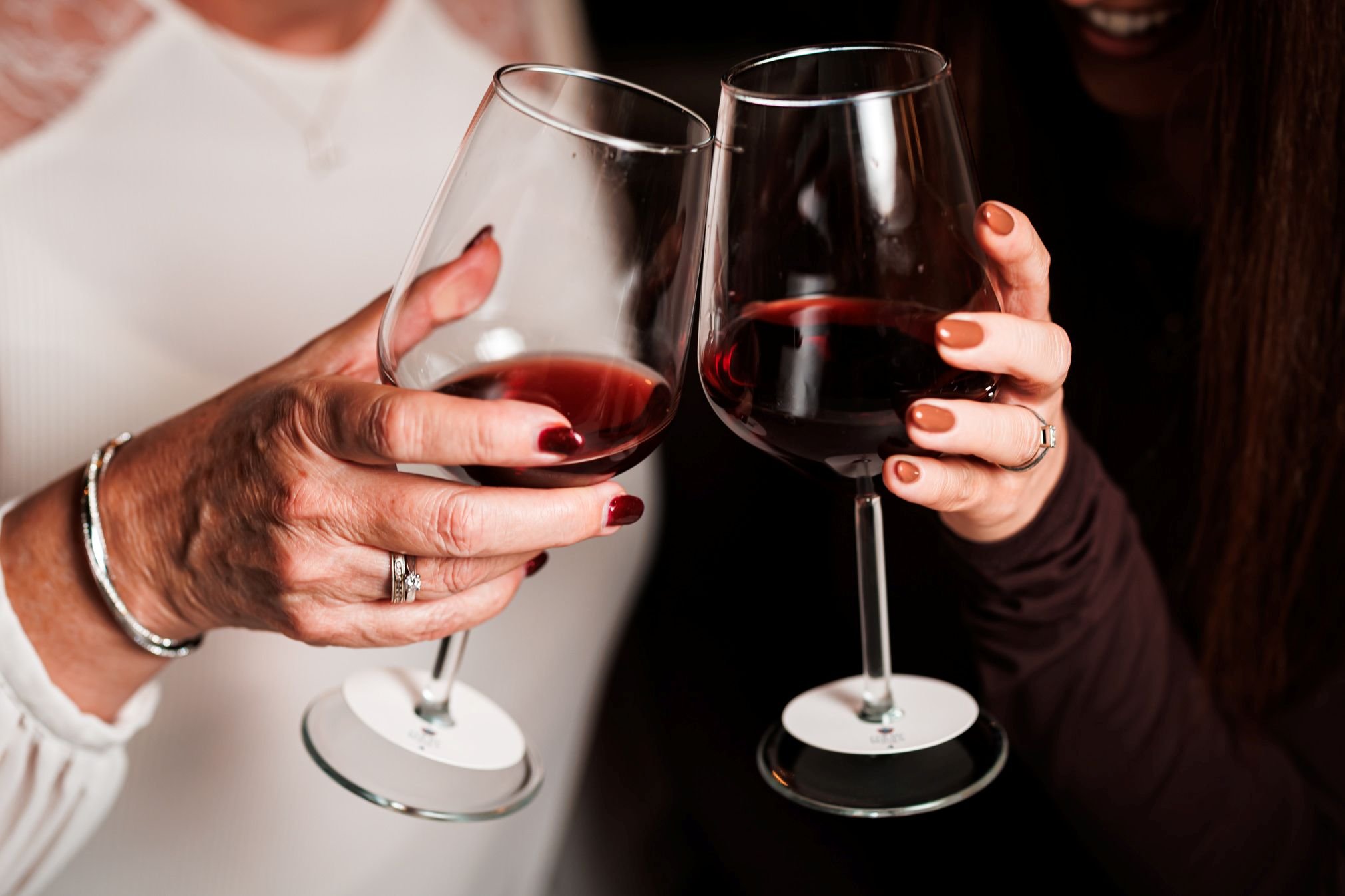 two friends clink glasses at a colby wines tasting on merseyside