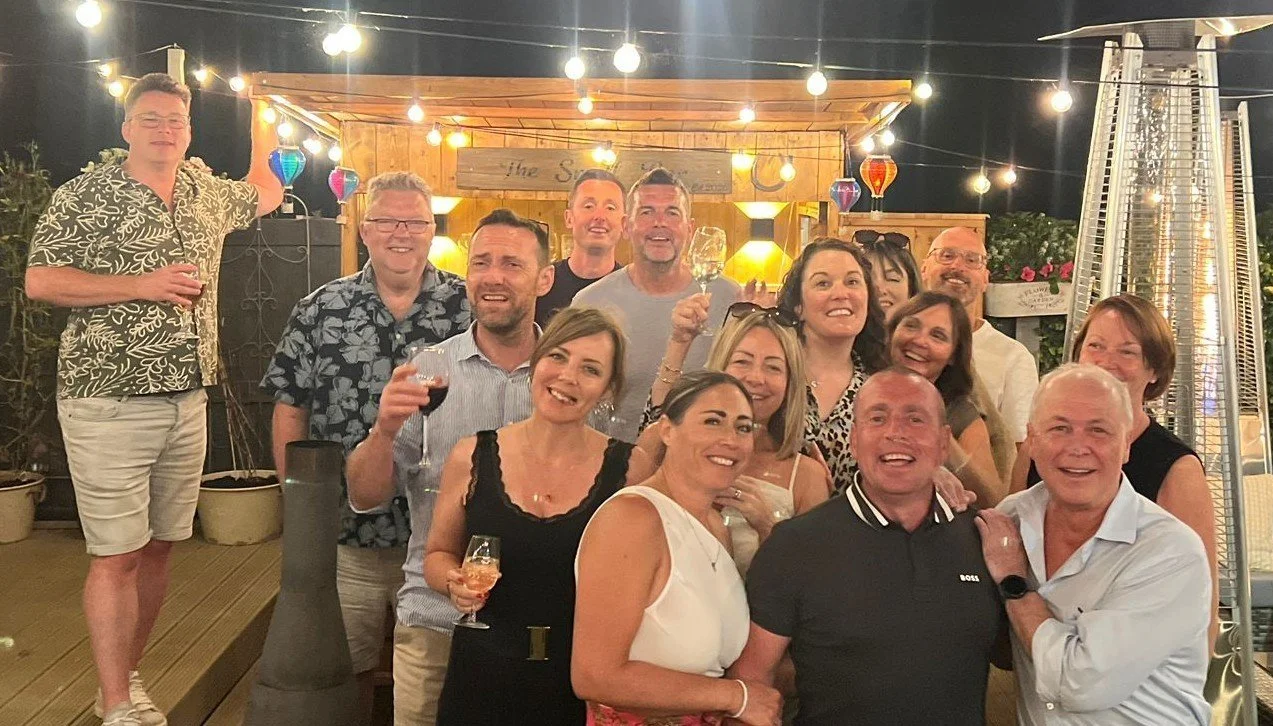 A lively group enjoying an outdoor garden wine tasting experience hosted by Colby Wines on The Wirral.