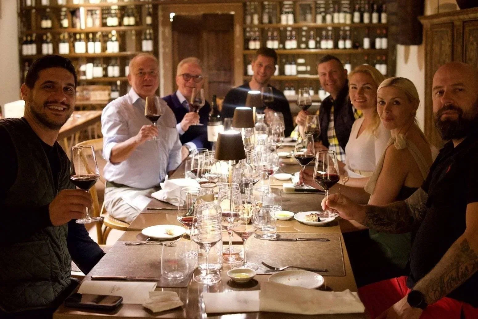 A private group enjoying an exclusive, candlelit estate dinner and wine tasting inside a historic vineyard cellar restaurant.
