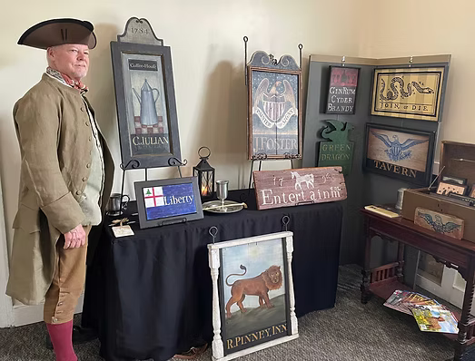 Jackson Foster stands next to his historic tavern signs at Williams Ordinary Tavern