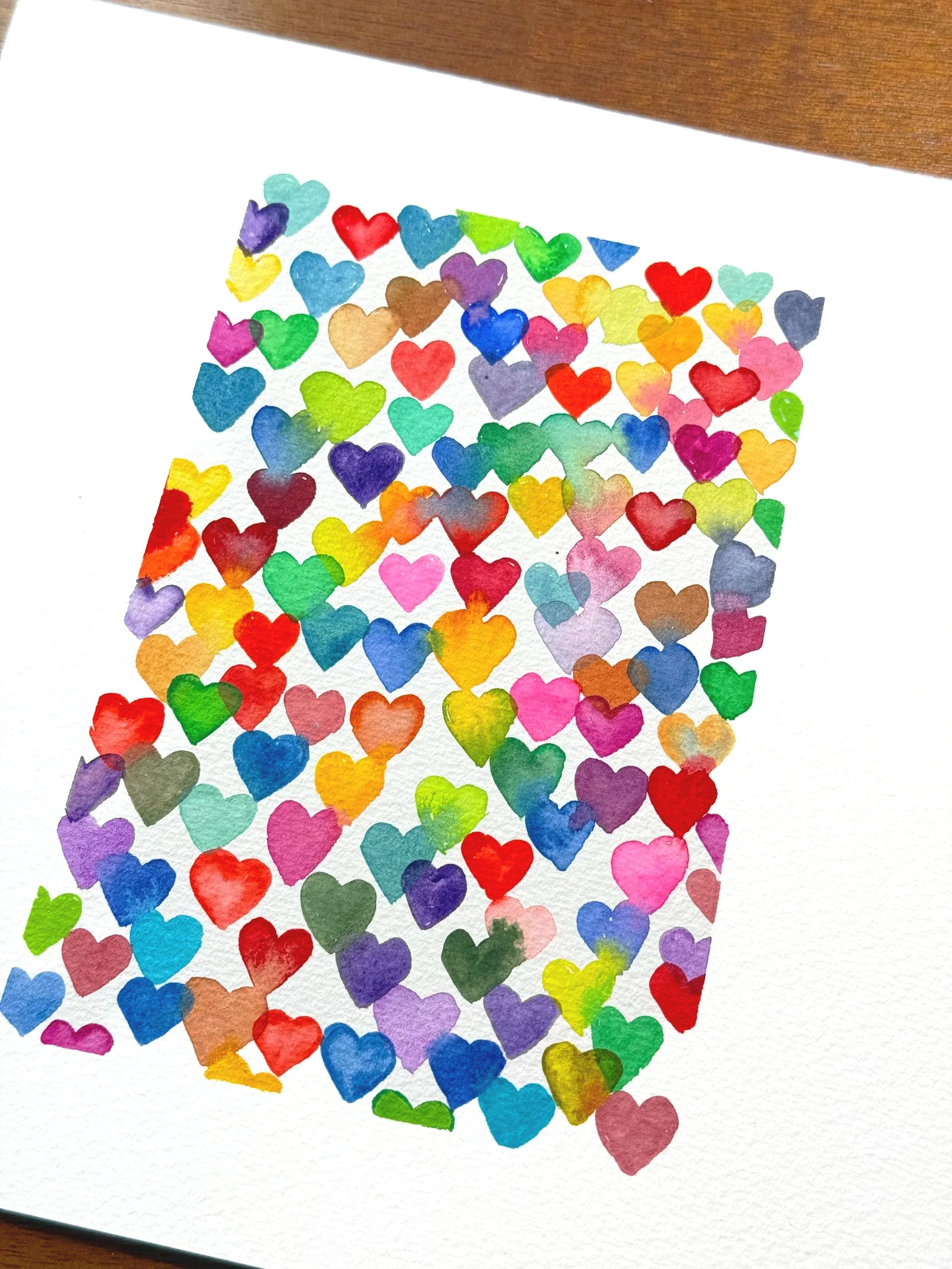 Colorful paper hearts arranged randomly on a white background.