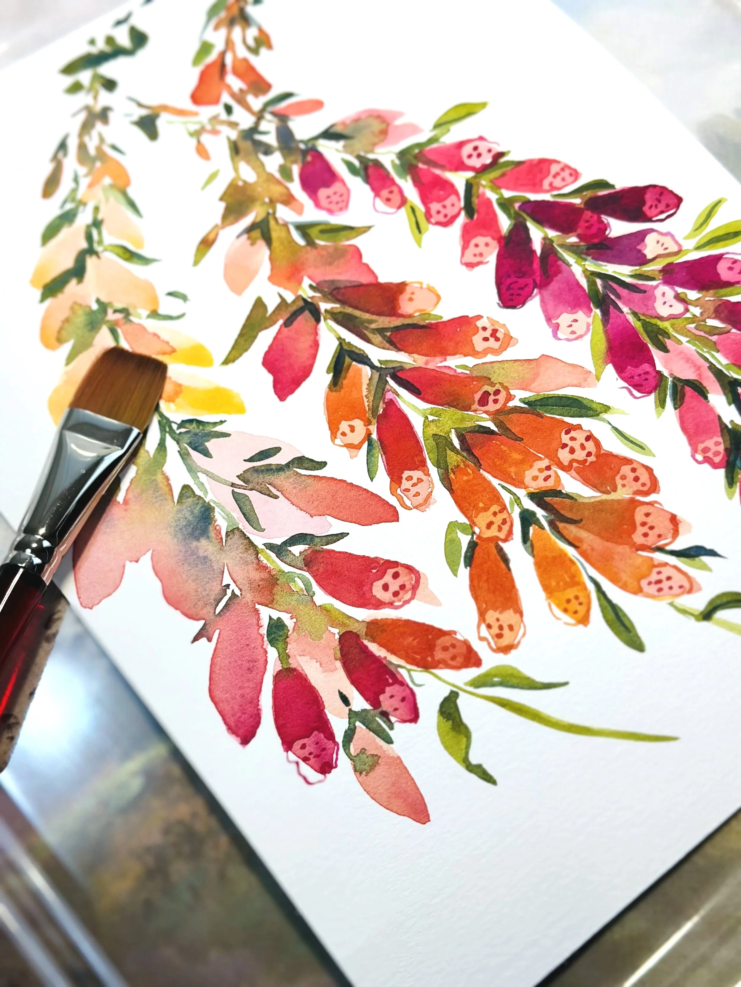 Watercolor painting of colorful leaves and berries on white paper with a paintbrush resting on the paper.