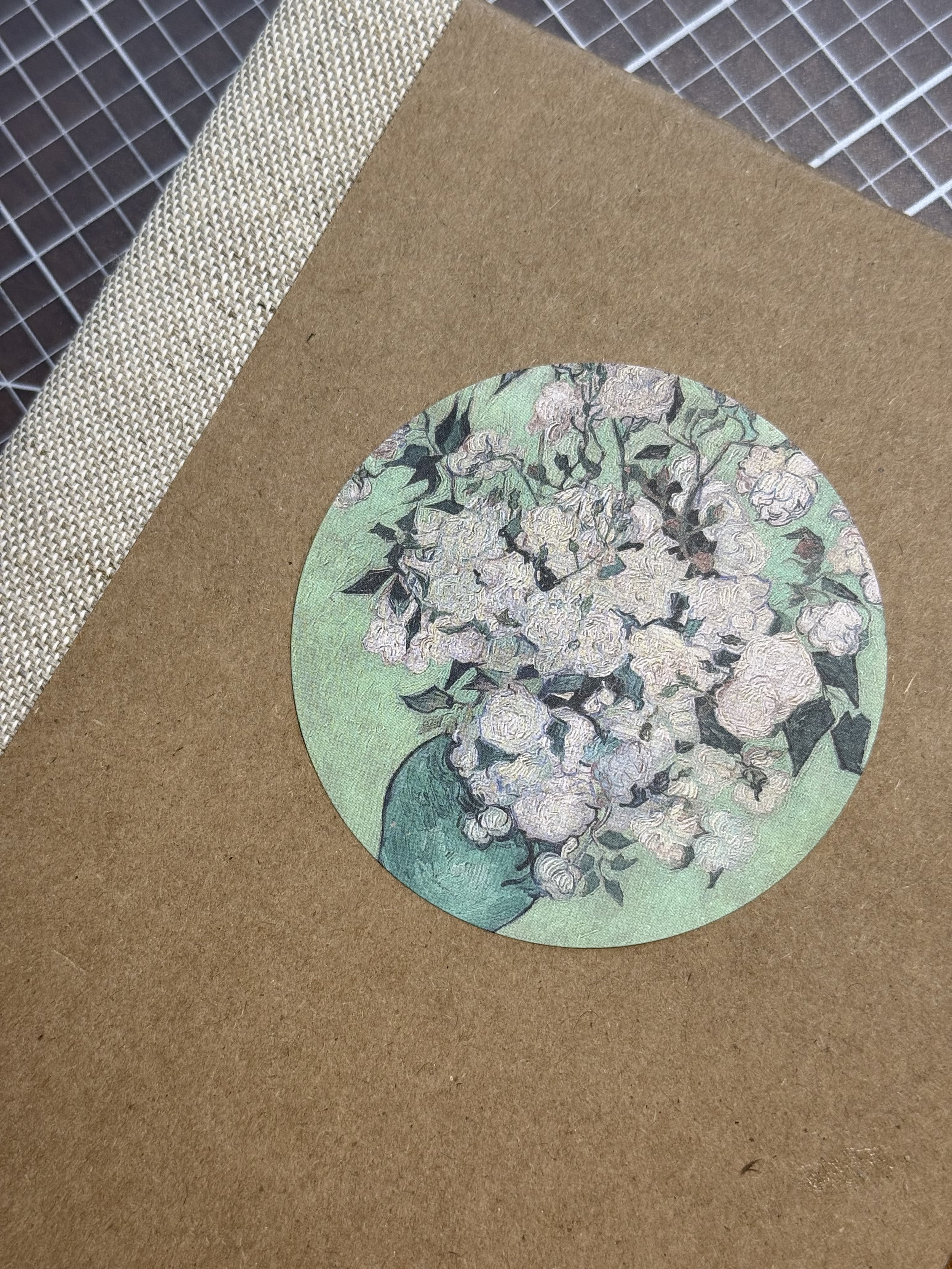 A brown paper package with a circular cutout of Vincent van Gogh's 'Almond Blossoms' painting on the front.