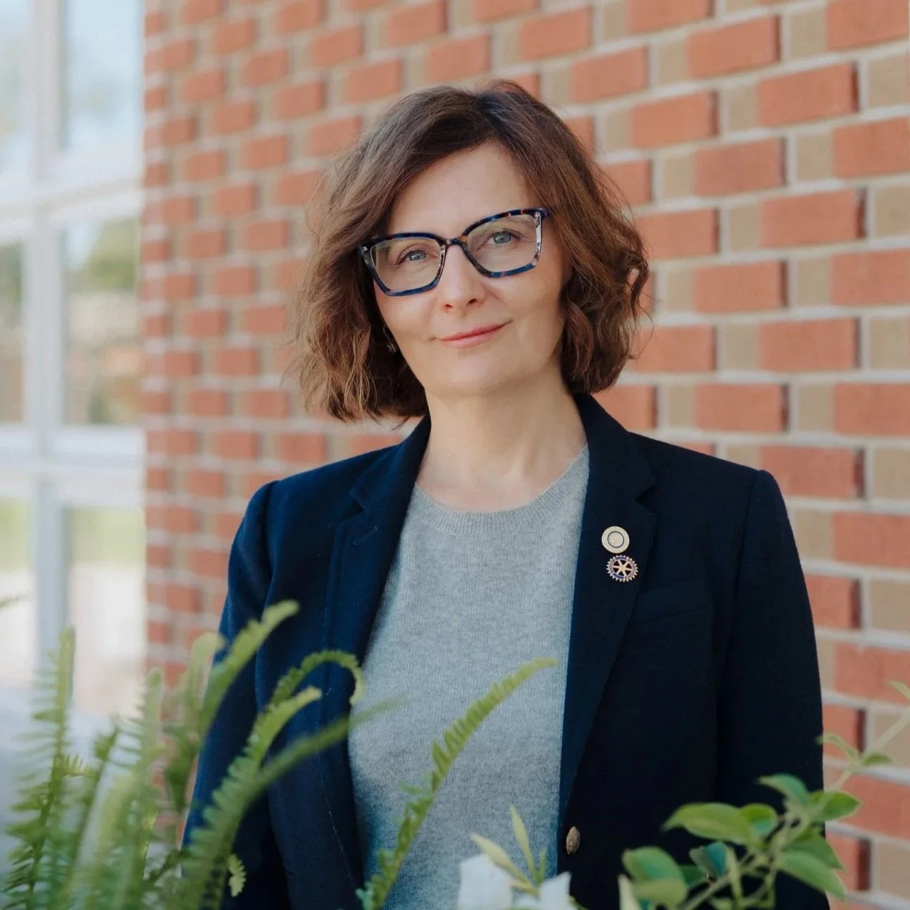 Dr. Patricia Nascu outside Acantha Clinic with flowers, symbolizing compassionate, refined medical aesthetics care in Stratford.