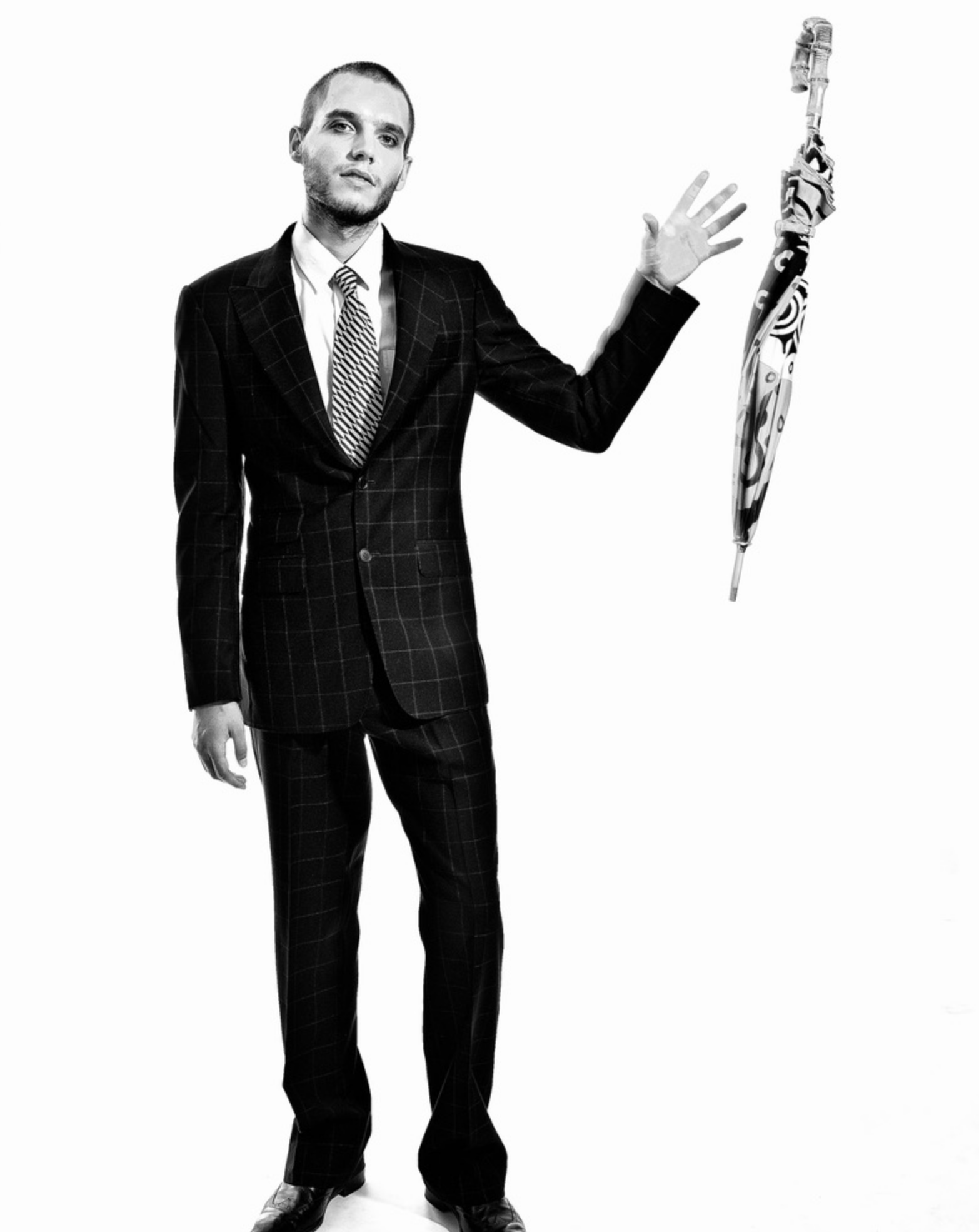 A man in a suit holding an open umbrella against a white background.